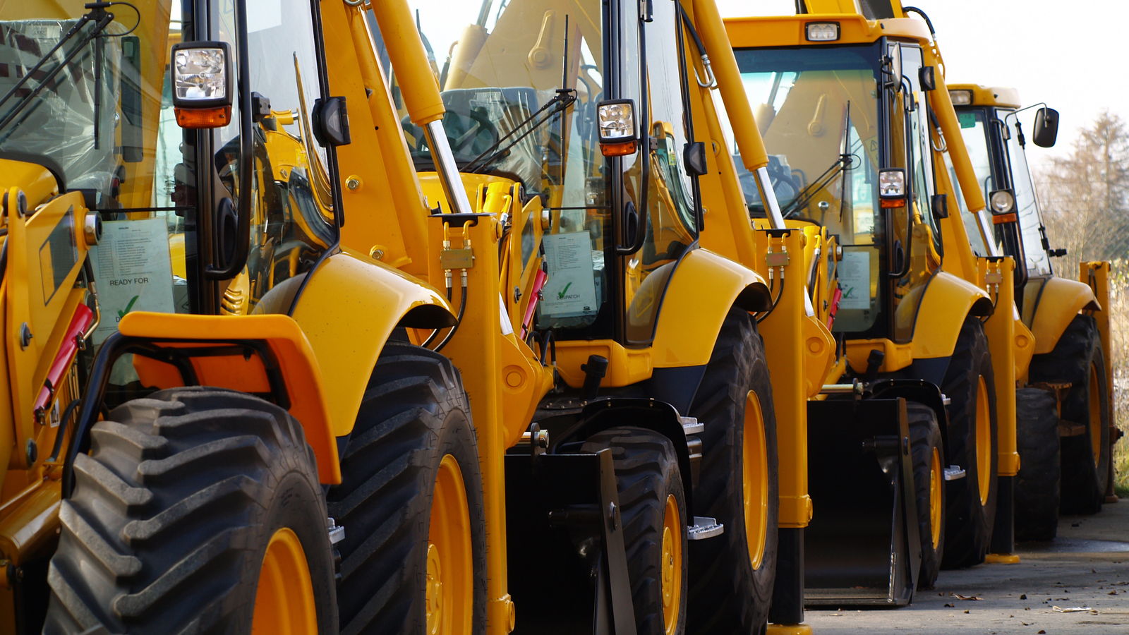 Backhoes lined up on a construction equipment dealer lot.
