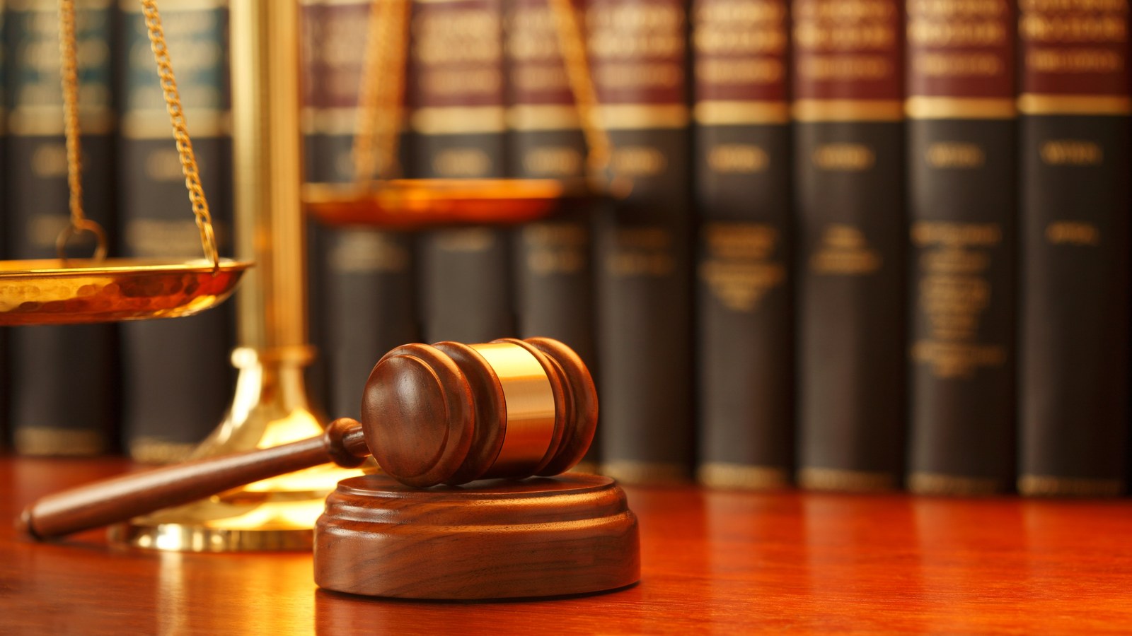 Gavel and scales of justice on a desk in front of law books.