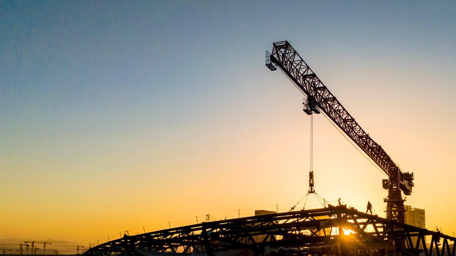 Crane at a construction site against a golden sky.