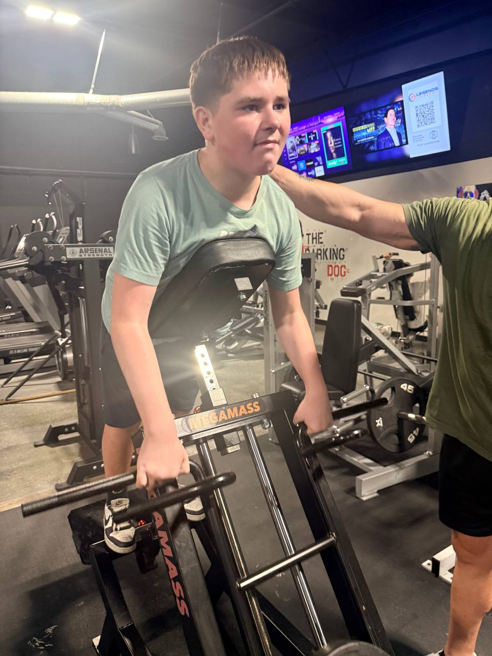 Coach Kevin Whitworth providing hands-on spotting and coaching on the Megamass squat machine
