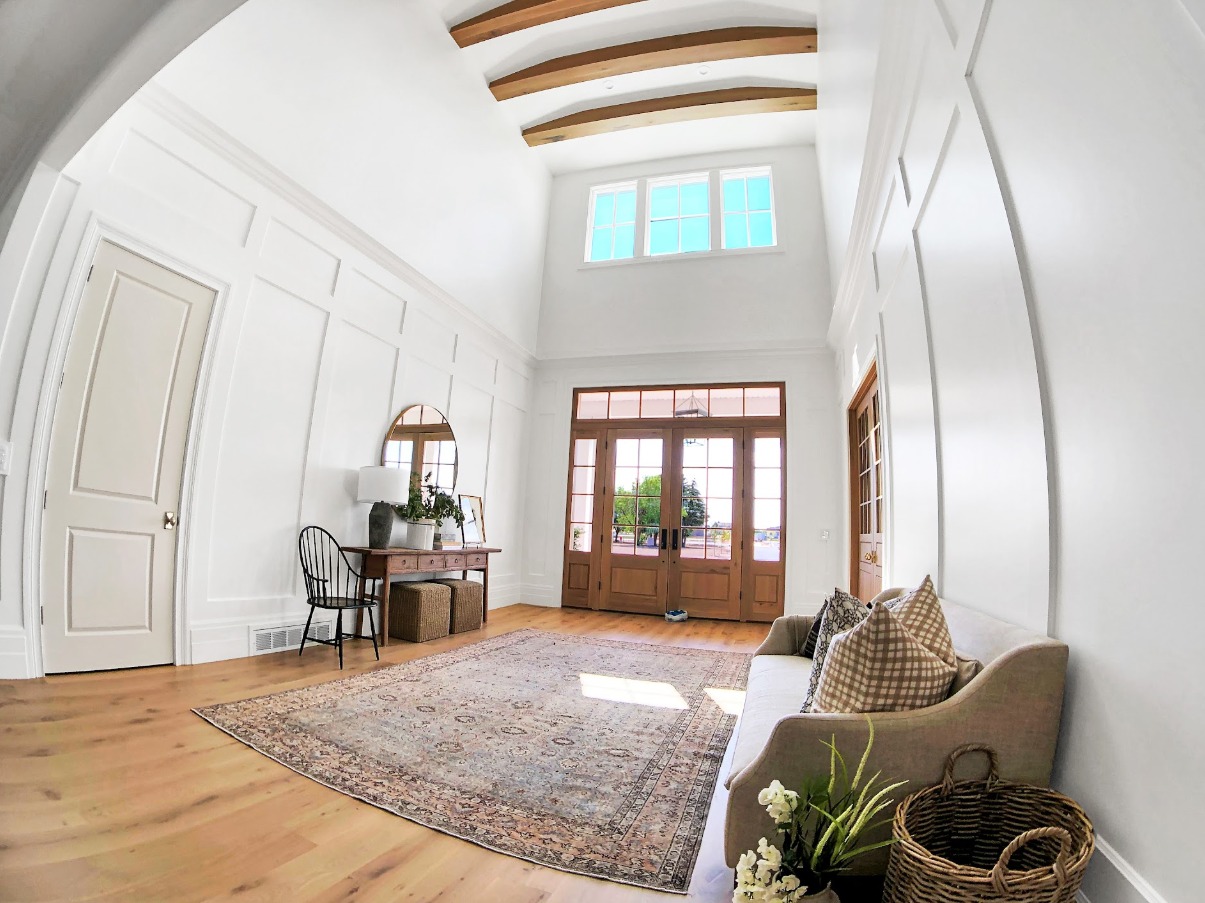 High ceiling entryway with custom wall paneling and wood beams