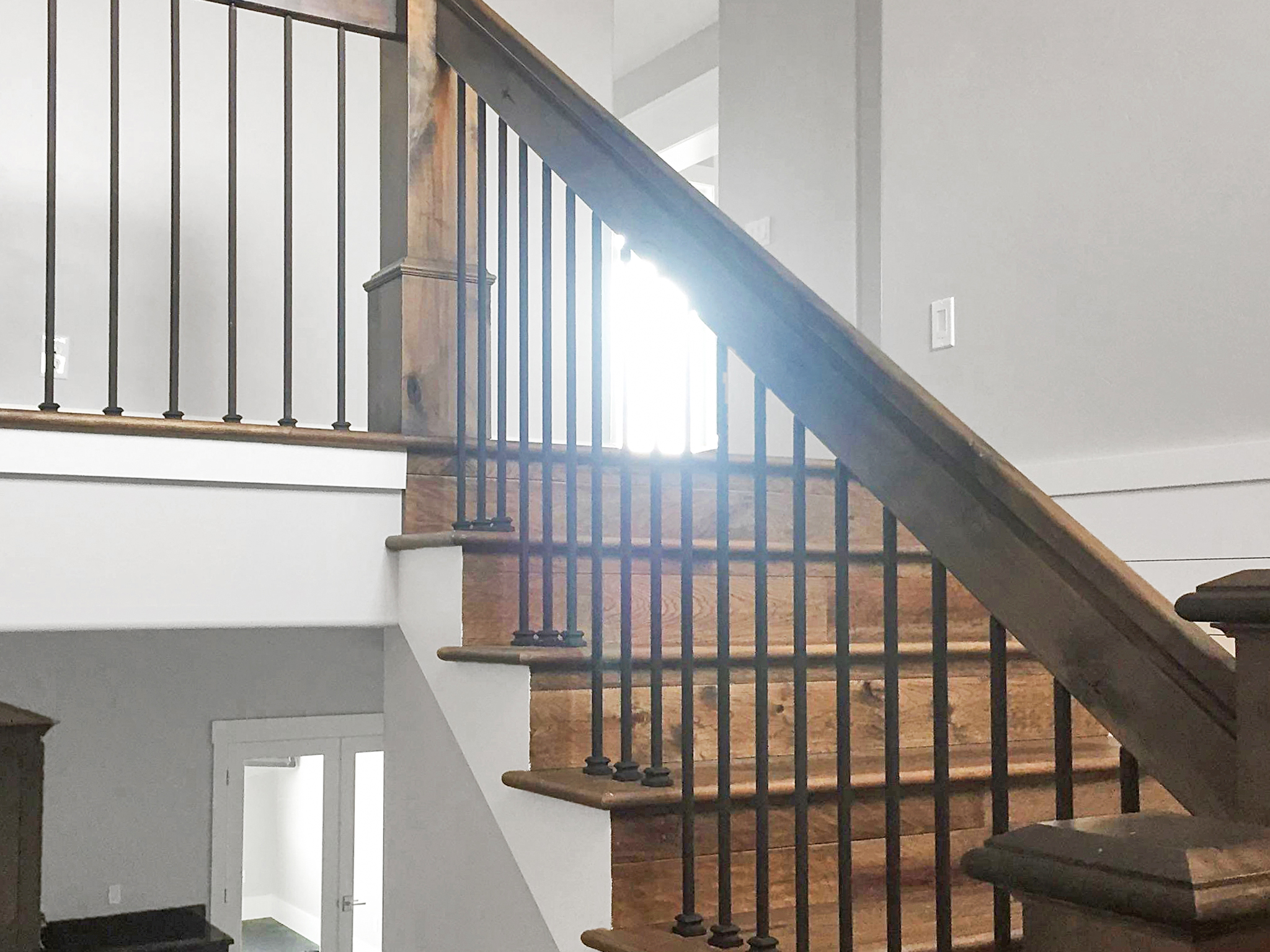 Custom wood staircase construction with rustic posts and iron balusters