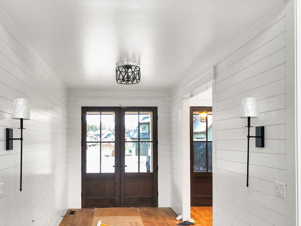 Hallway with shiplap wainscoting and custom lighting