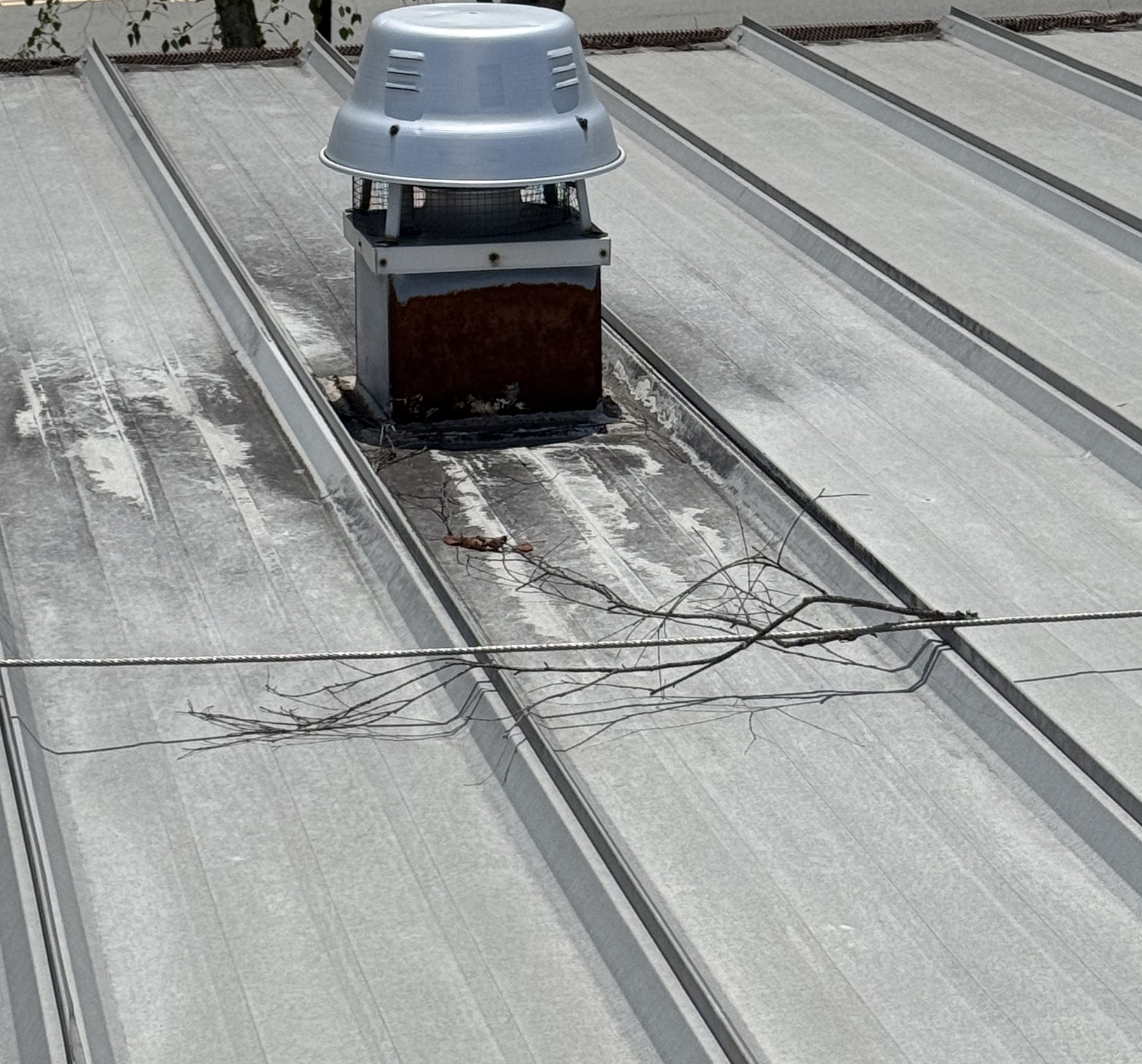 Roof exhaust vent and curb with existing repair material on metal panels