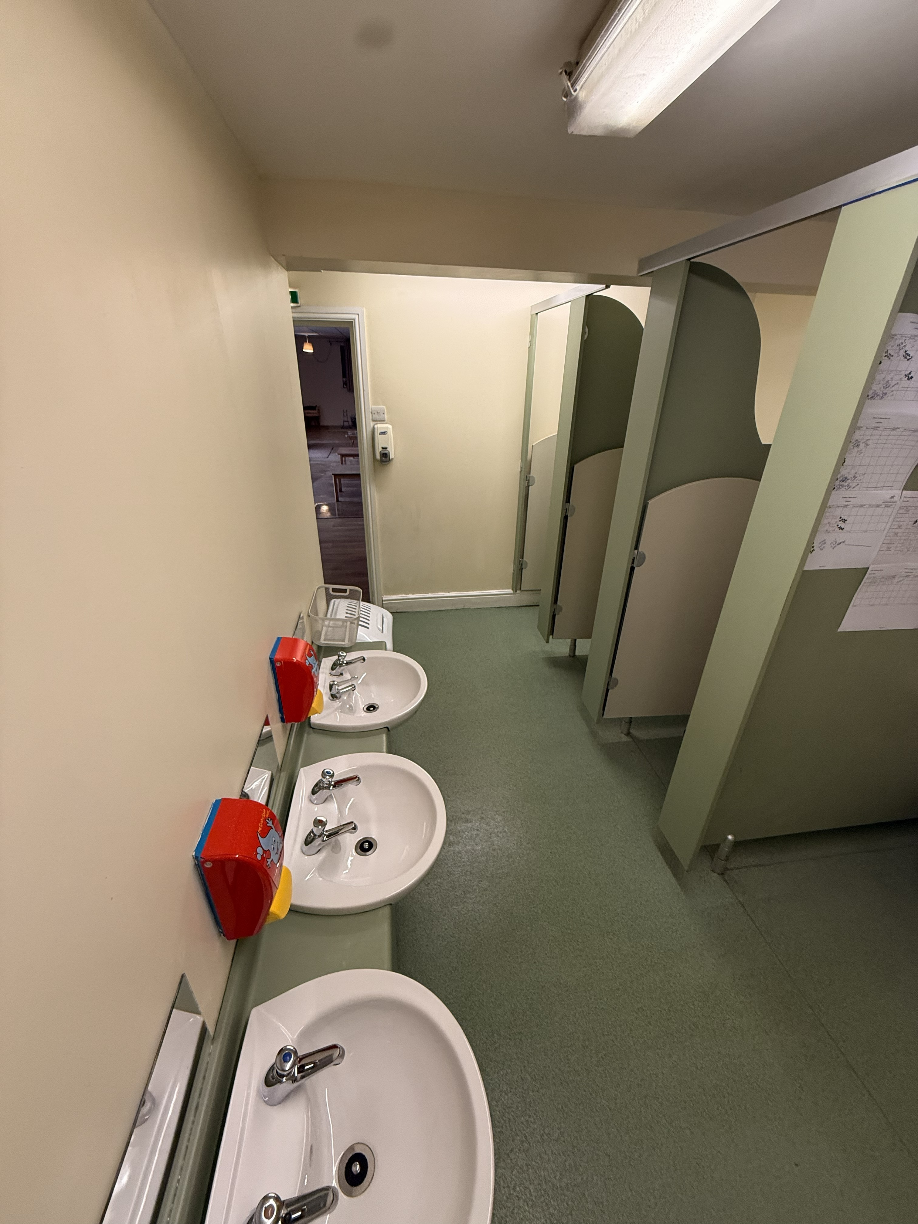 Clean commercial restroom with green cubicles and white sinks - Crystal Clean sanitisation service