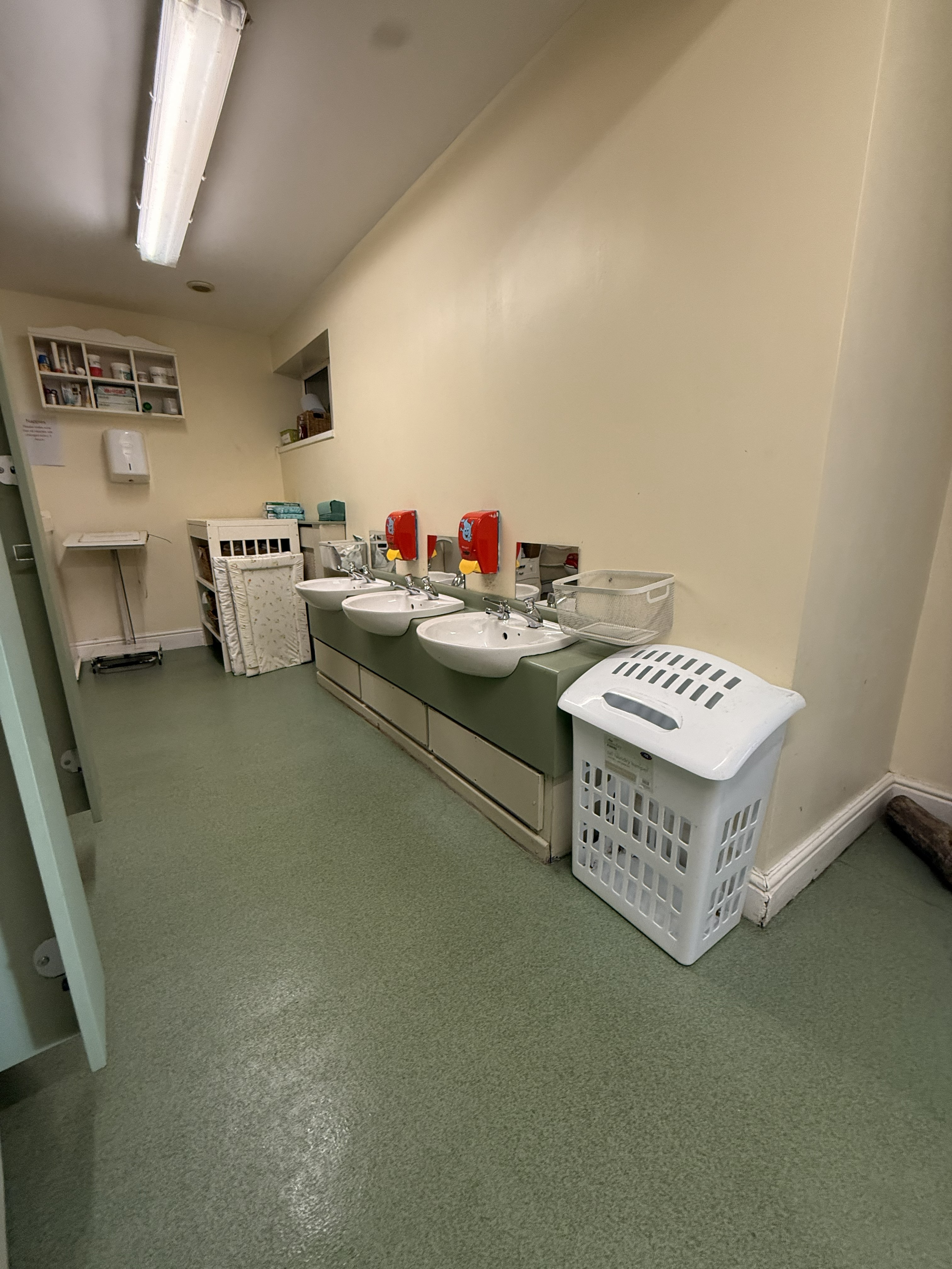 Children's bathroom facility with triple sinks and green counter - professionally cleaned by Crystal Clean