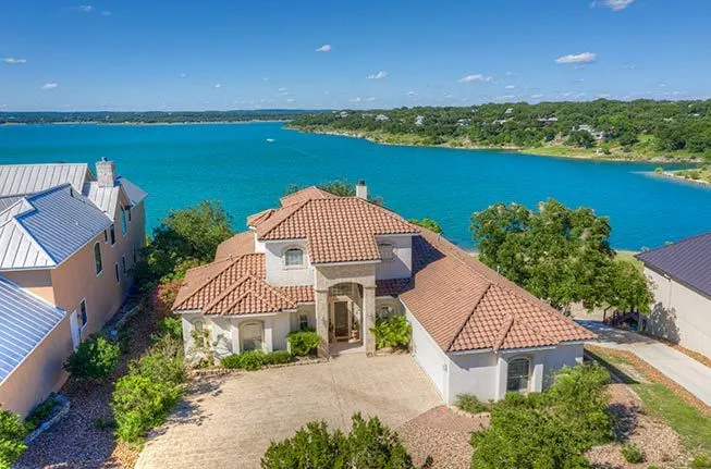 Aerial view of a beautiful lakeside home with a red tile roof overlooking Canyon Lake