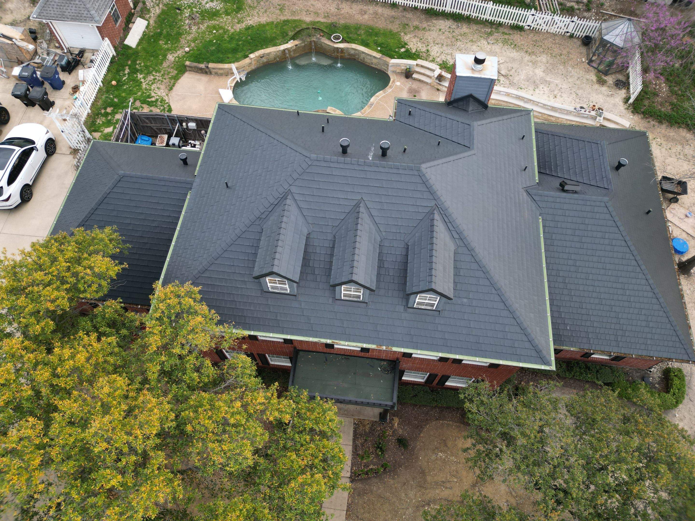 Aerial view of completed metal roof installation on luxury brick home