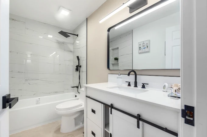 Bathroom renovation by Builders For You Construction with marble tile, soaking tub, and black fixtures in Yuma, AZ