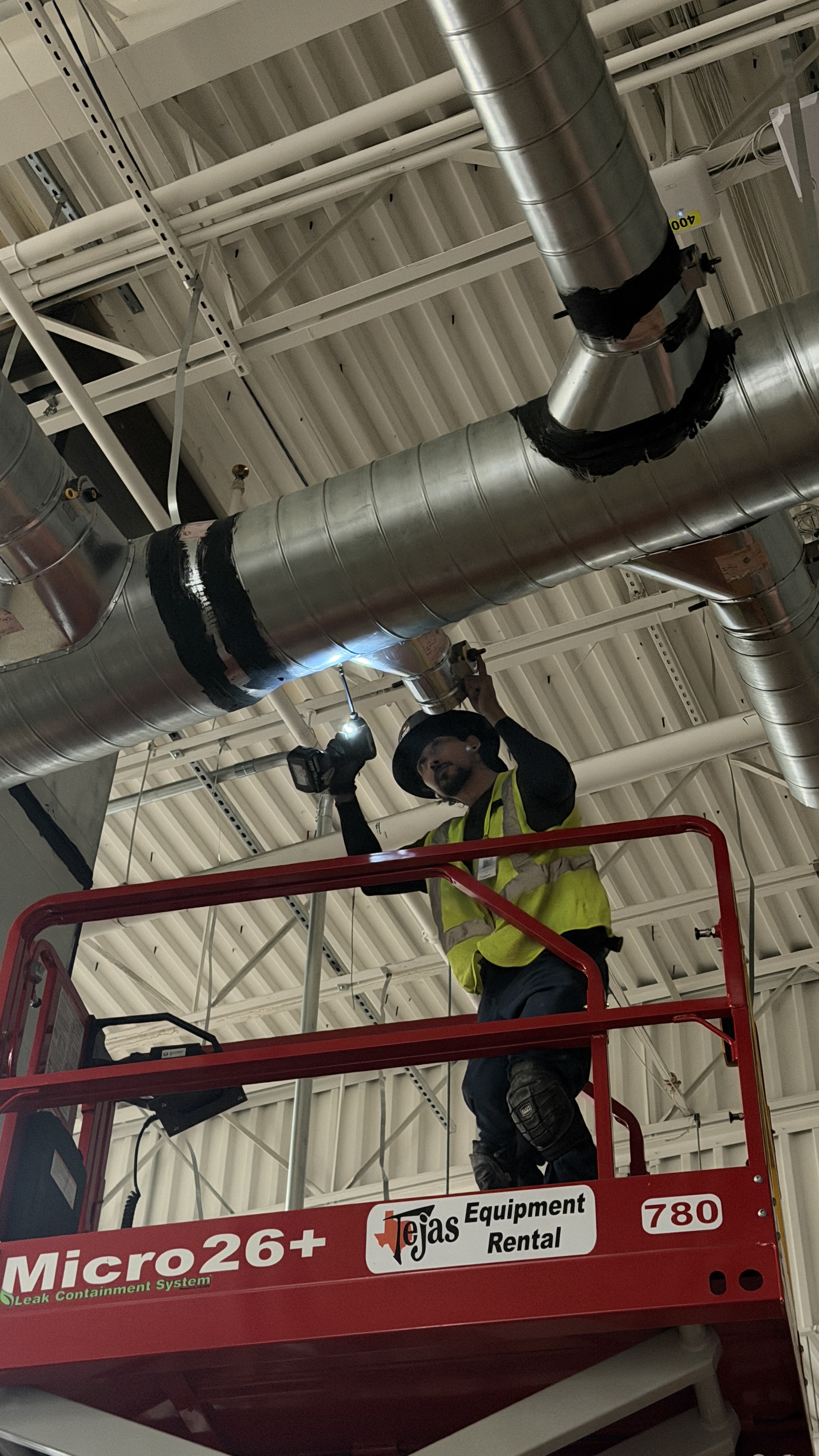 Alpha HVAC Tech on Scissor Lift Installing Spiral Ductwork