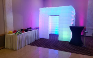 Enclosed white square LED inflatable photo booth rental with glowing purple lights and a side door at a Valparaiso Indiana wedding reception.