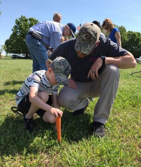 Adult and child metal detecting together at a hunt event