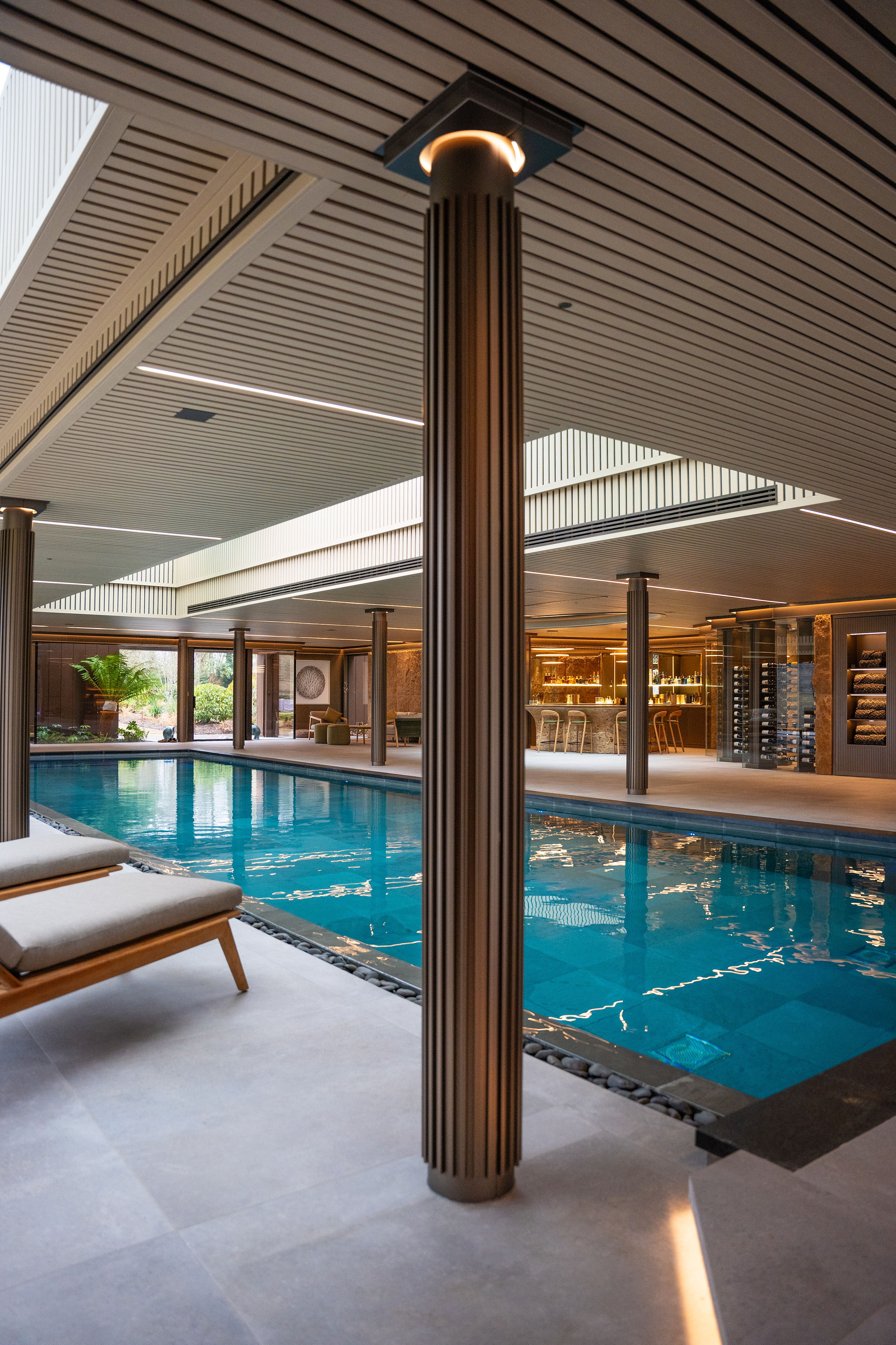 Bespoke indoor pool hall with fluted architectural columns and lounge bar by Poolcourt