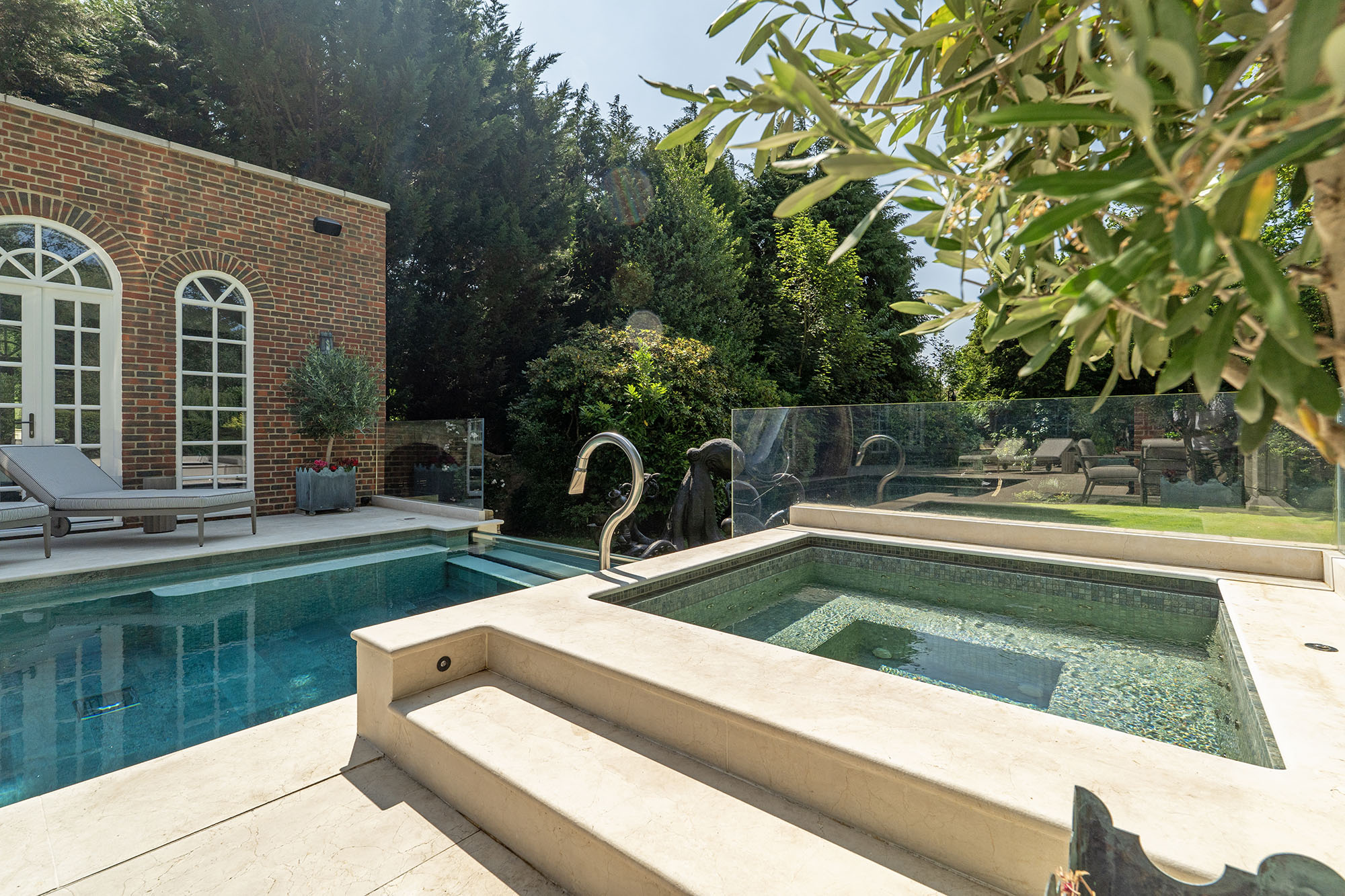 Luxury swimming pool with integrated hot tub and stone terrace by Poolcourt