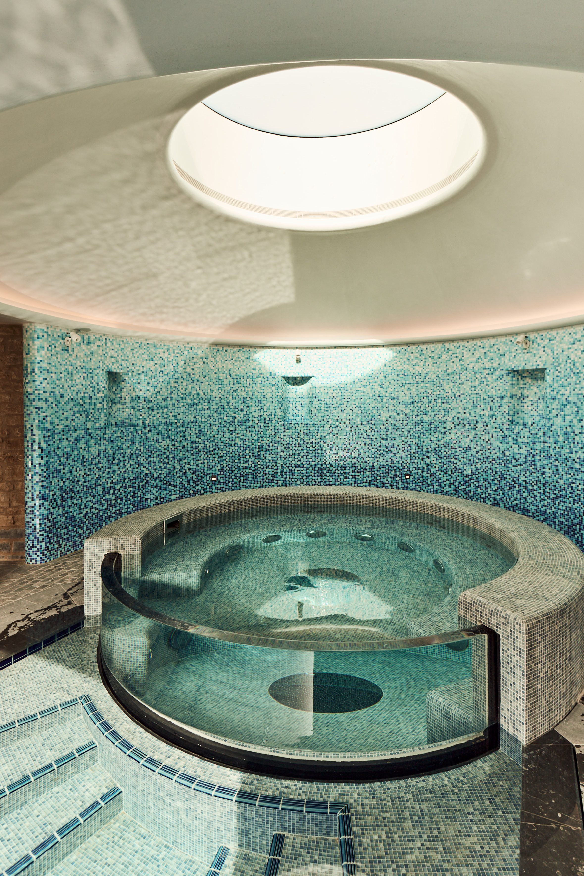 Curved mosaic vitality spa pool with skylight and glass wall by Poolcourt