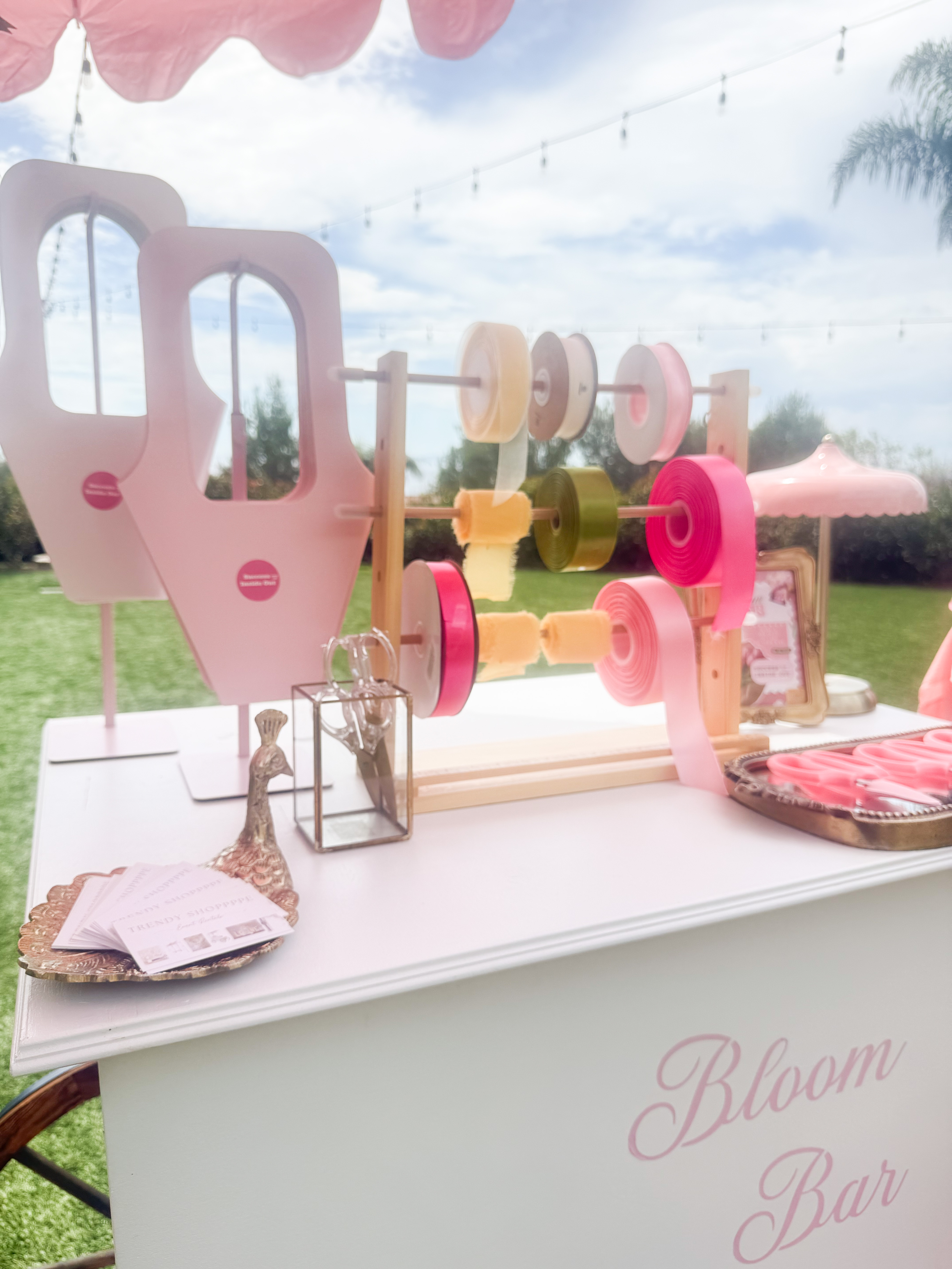 Bloom Bar table setup with colorful ribbon spools, scissors, and floral sleeves