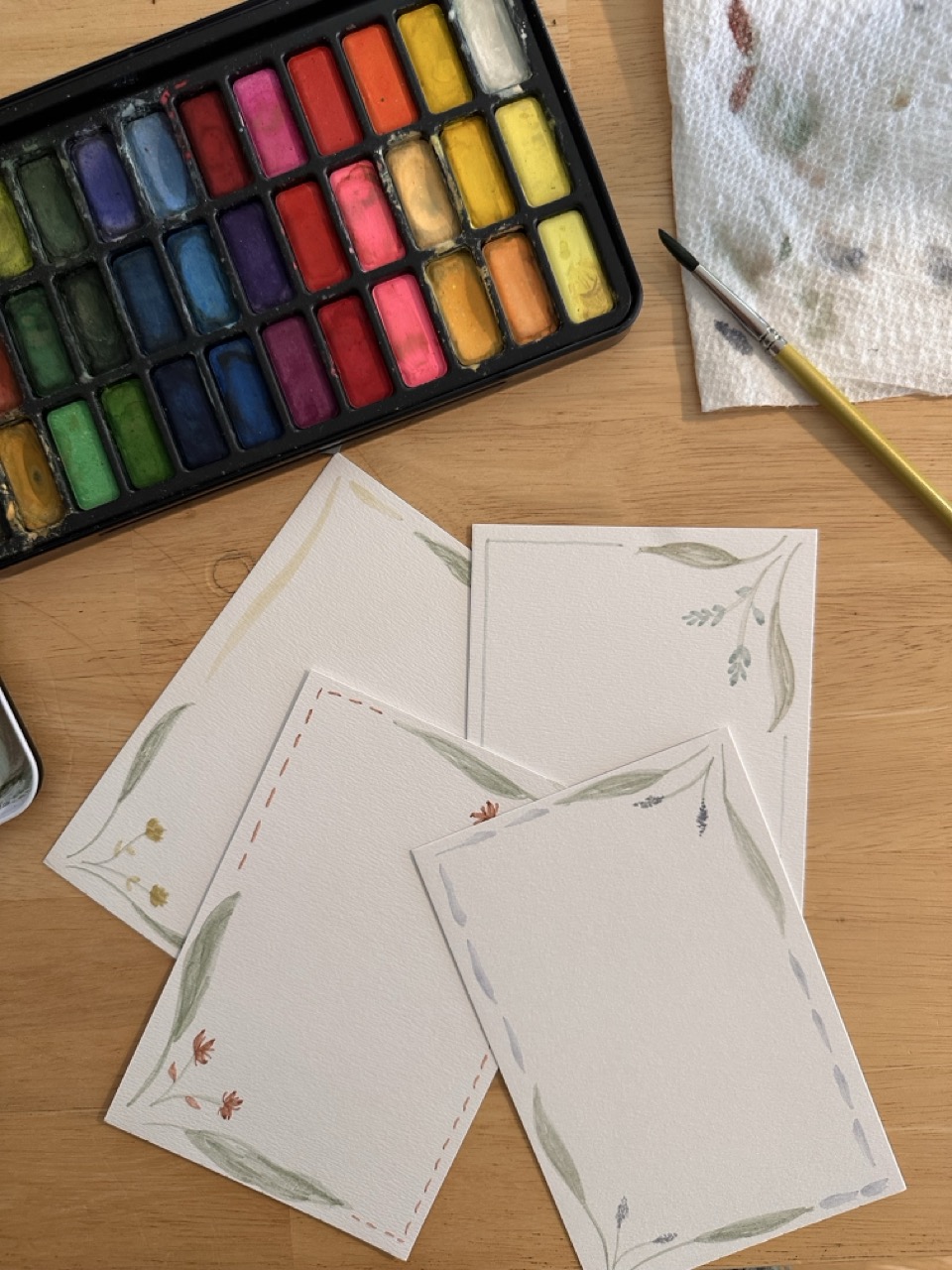 Hannah's watercolor paints and hand-painted floral stationery on her work table