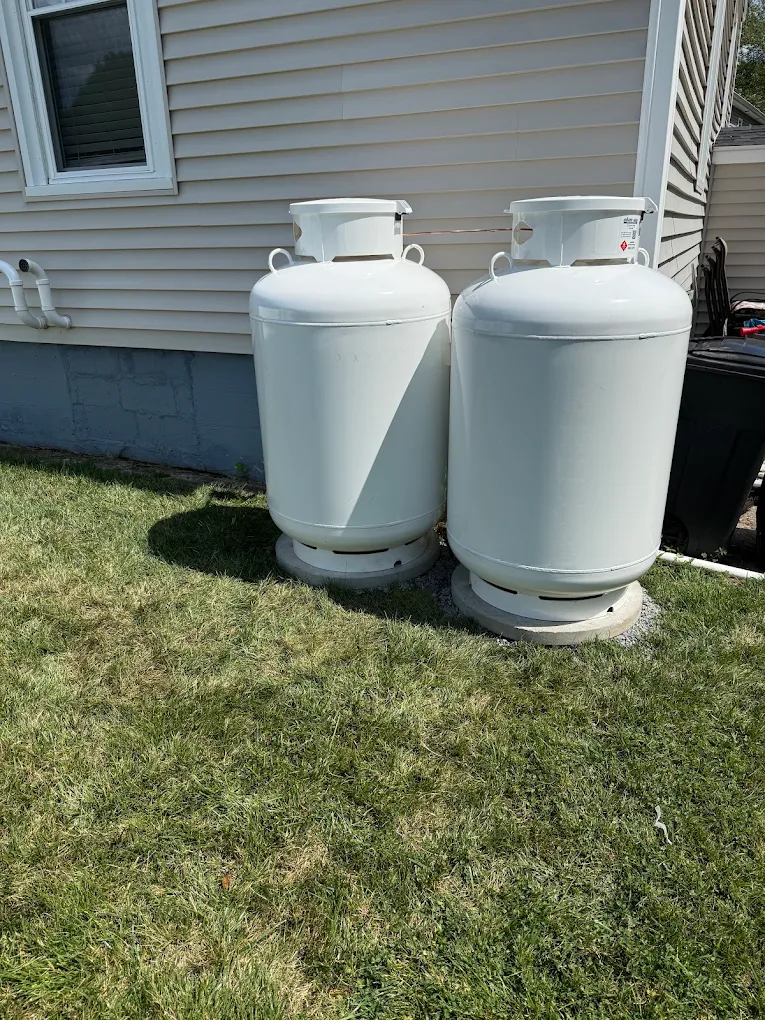 Two vertical propane tanks properly placed on concrete pads next to a home's exterior wall