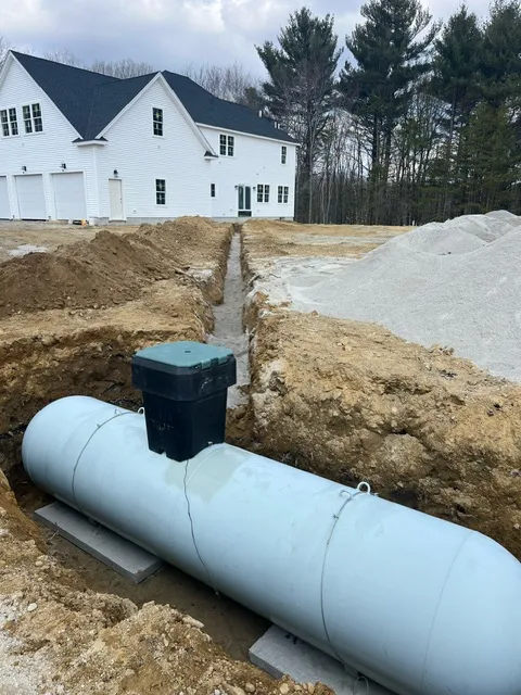 An underground propane tank being installed at a new home construction site with excavation trenches visible