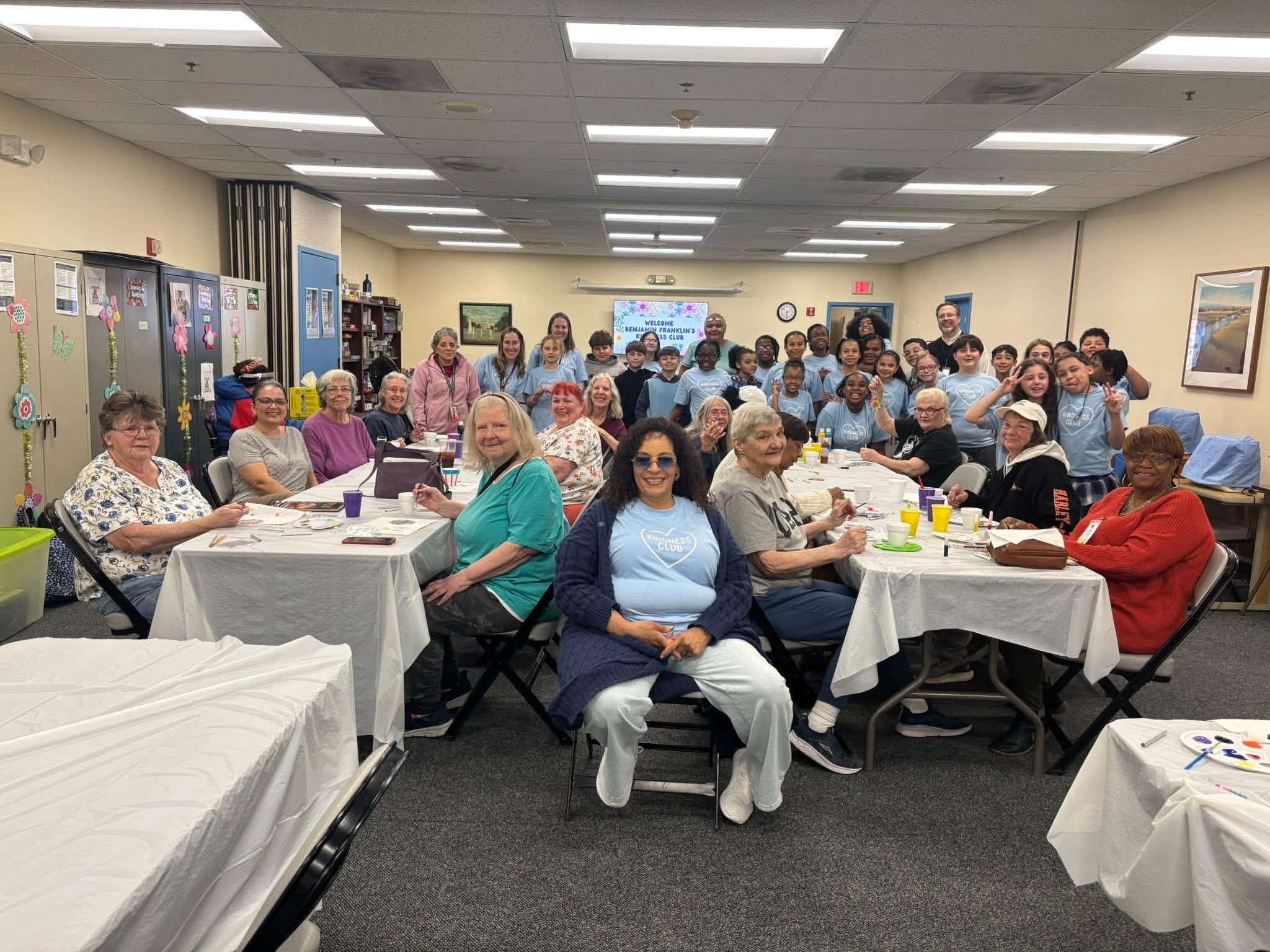 Daisy Olivo seated with Benjamin Franklin's Kindness Club gathering of youth students, seniors, and community members