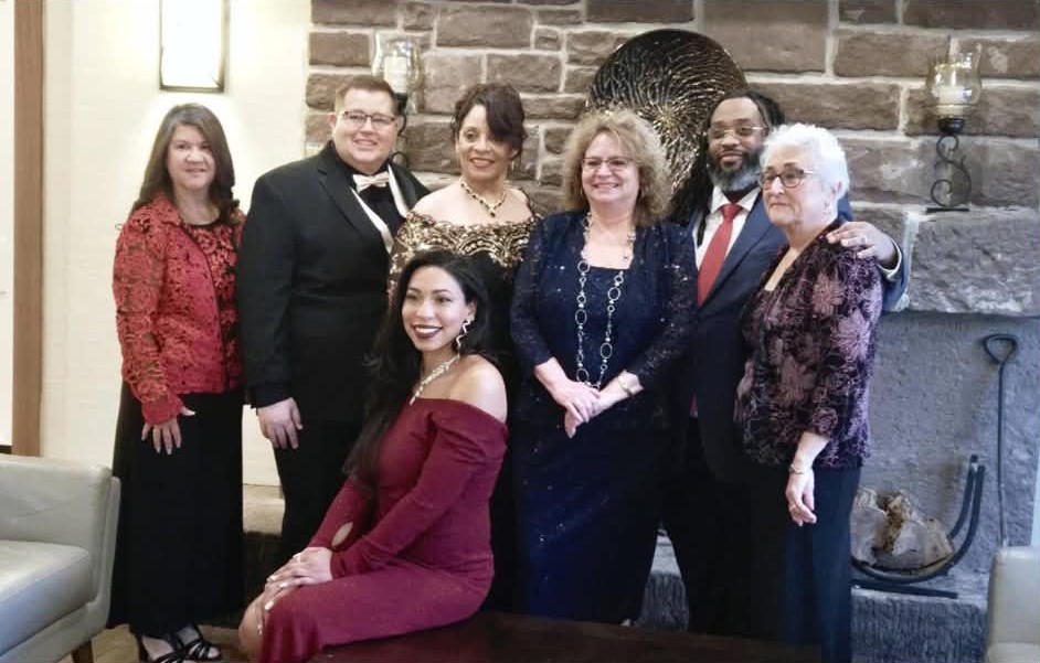 Daisy Olivo with community leaders and colleagues gathered for a formal portrait by a fireplace