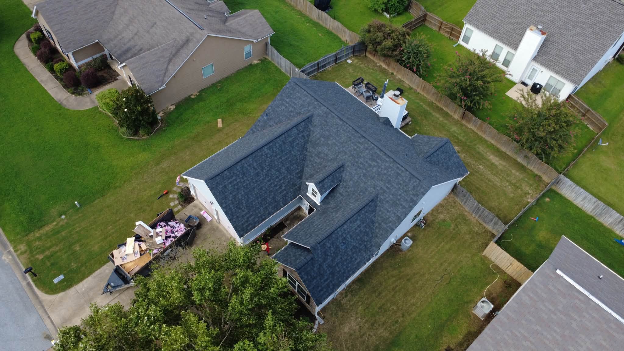 Aerial drone photo of completed dark gray architectural shingle roof replacement on white two-story home in Central Alabama showing clean shingle lines and professional installation