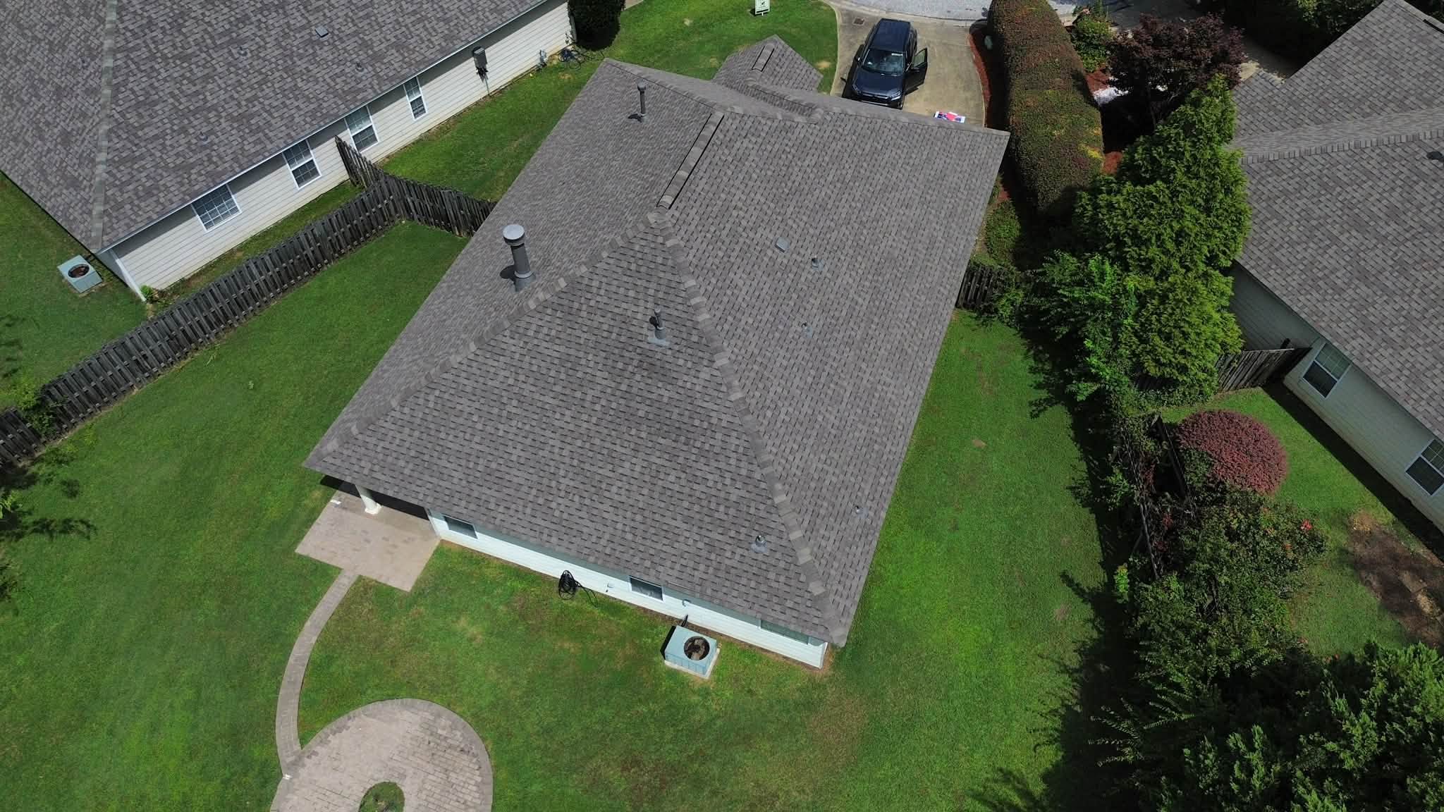 Aerial view of newly completed gray architectural shingle roof on light blue ranch style home with proper ventilation and clean hip roof design