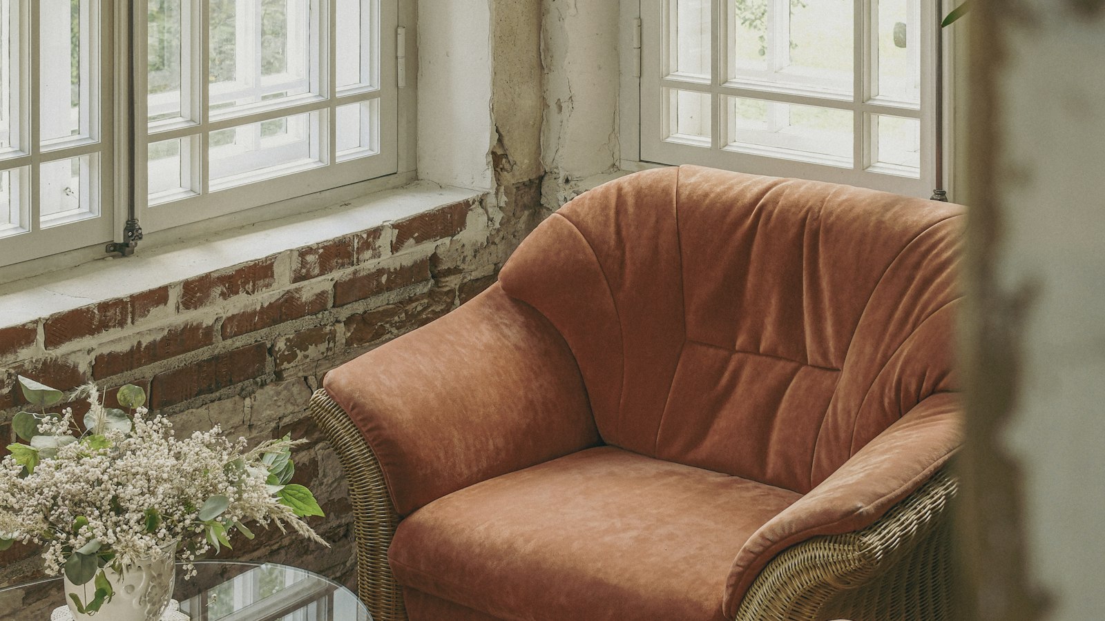 Empty armchair beside tall windows in a quiet rustic room