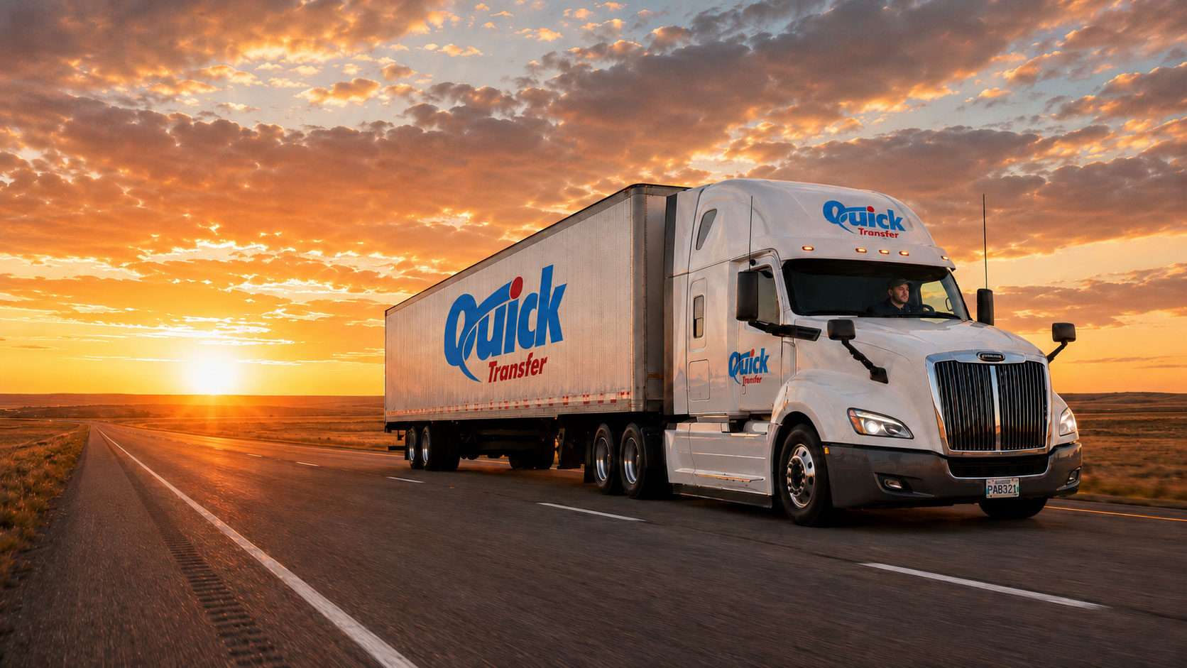 Quick Transfer branded semi truck driving across the Manitoba prairie at sunset