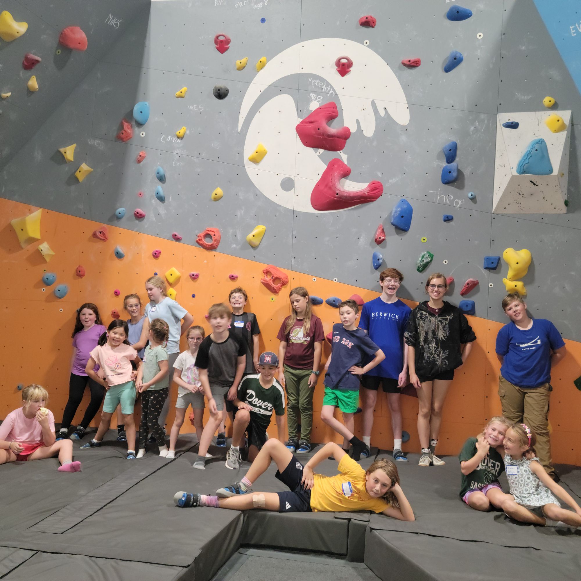 Group of kids posing in front of the climbing wall