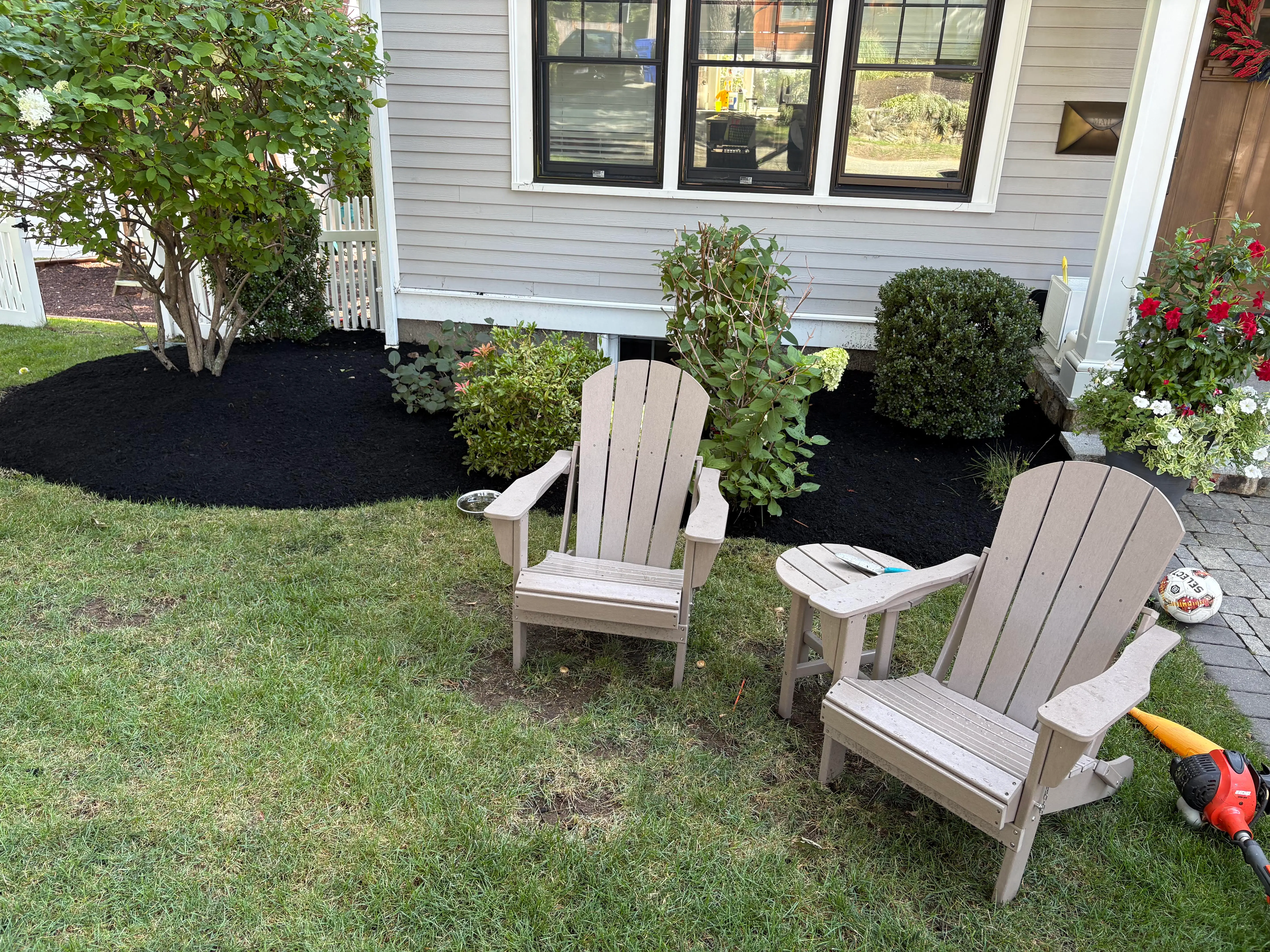 Freshly mulched garden bed with Adirondack chairs, Arlington, MA