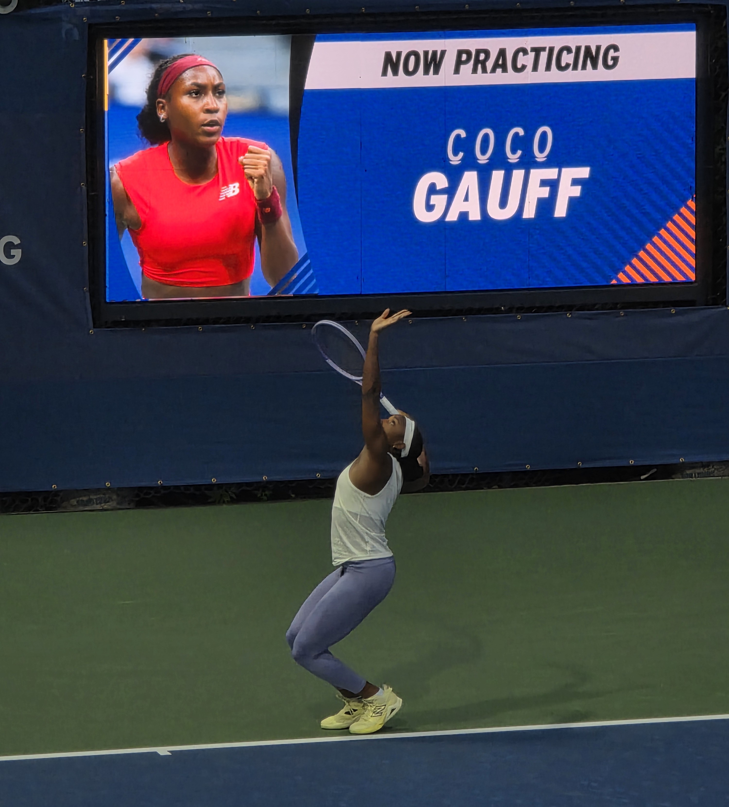 Coco Gauff practicing on an outer court at the US Open with fans watching nearby