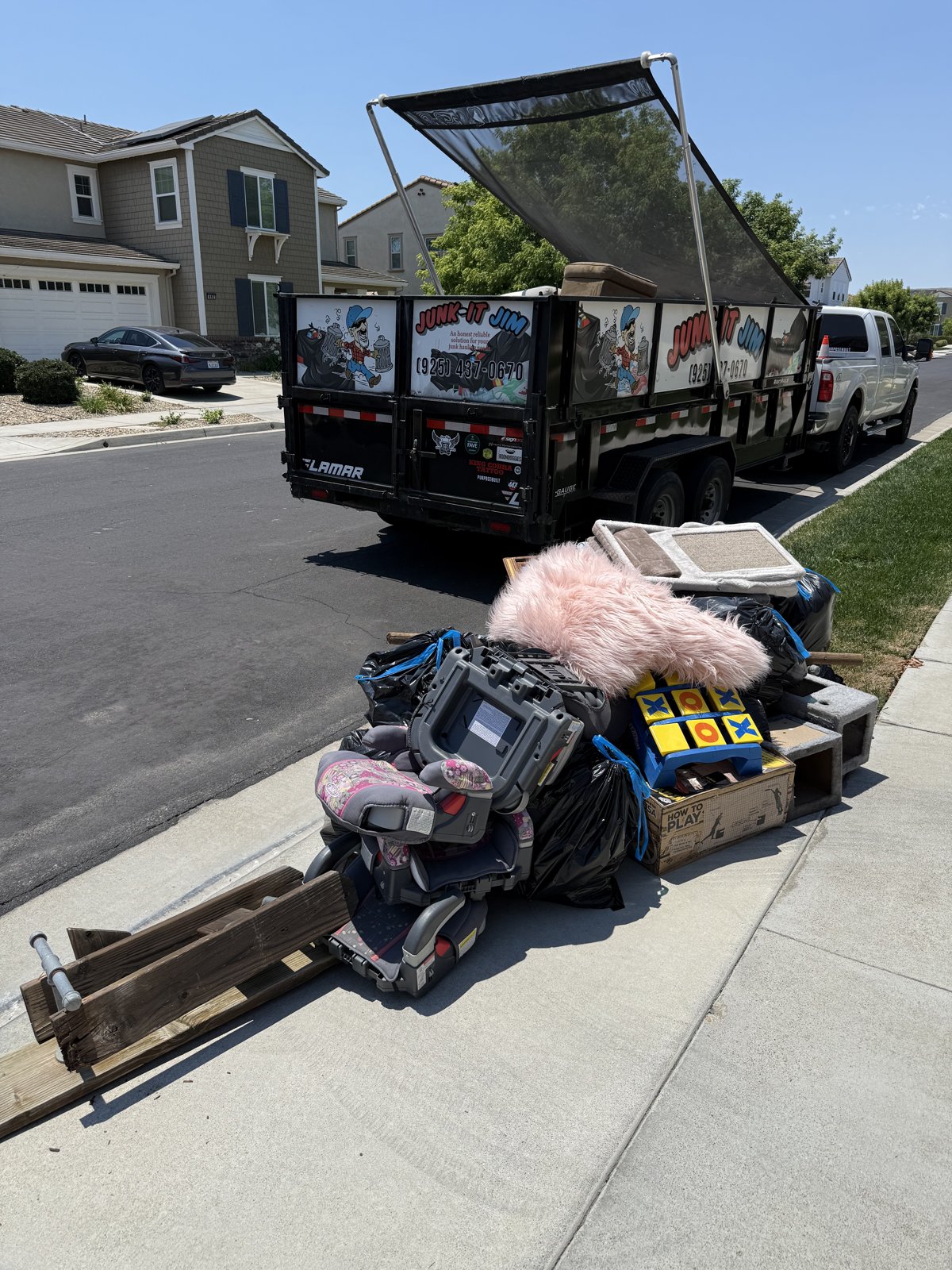 Junk It Jim trailer loaded with junk at a curbside pickup in the East Bay