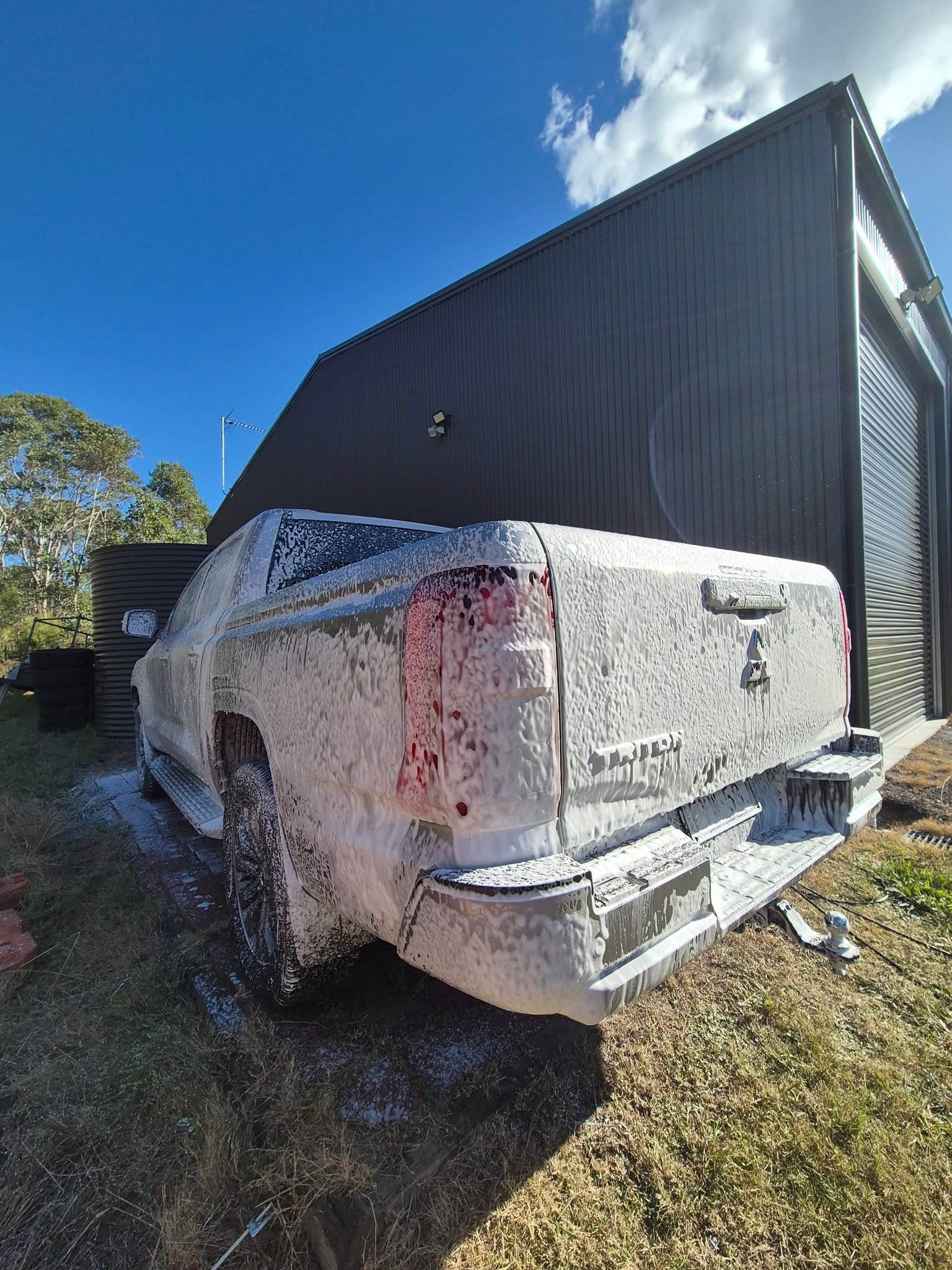Mitsubishi Triton pickup truck covered in thick snow foam during a pre-wash stage at Groom Garage