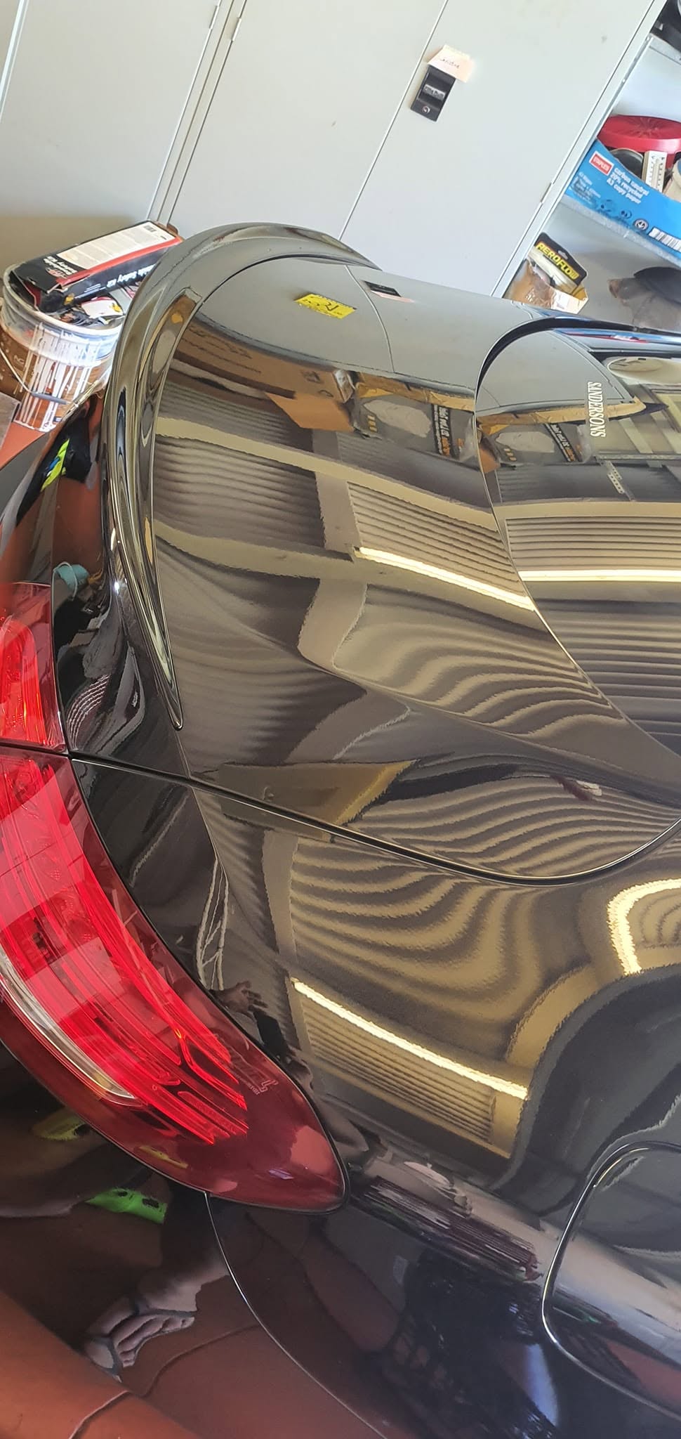 Close up of black Mercedes rear quarter panel showing mirror-like paint reflection from professional paint correction