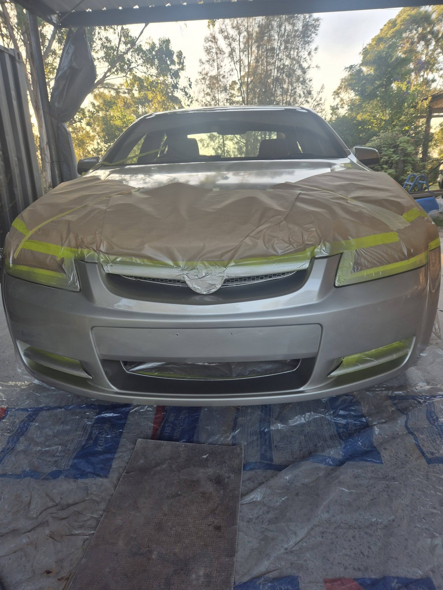 Silver car front end prepped with tape for paint correction