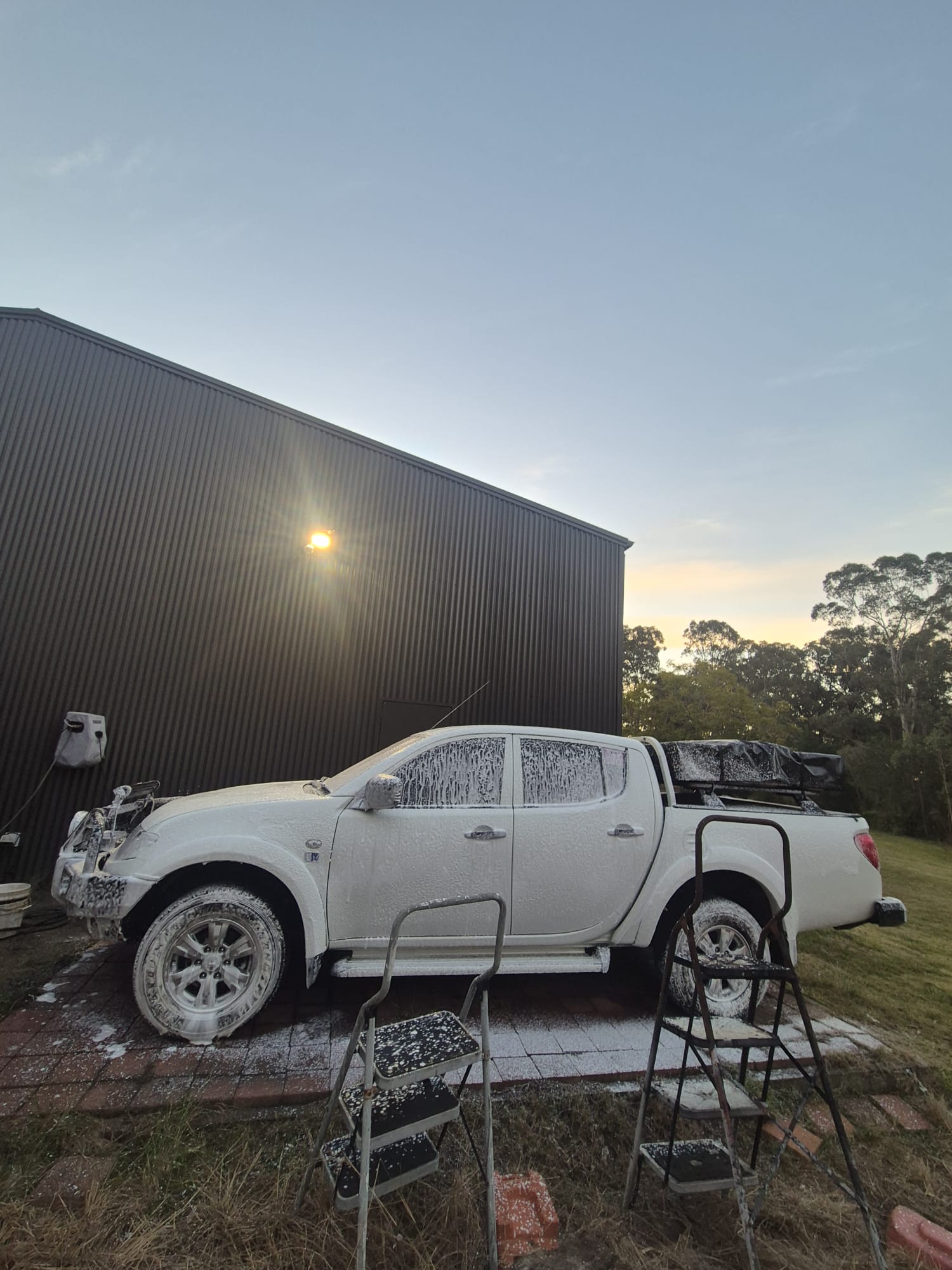 Mitsubishi Triton pickup truck covered in thick snow foam during a detailing session at Groom Garage