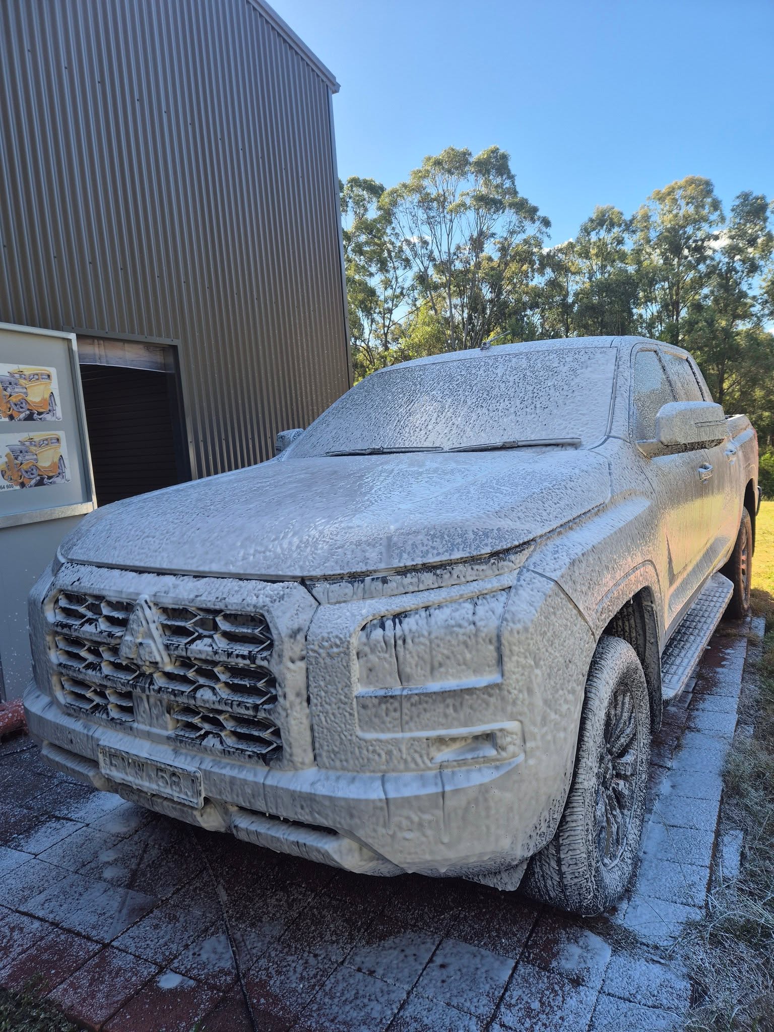 Mitsubishi Triton pickup truck covered in thick snow foam during a pre-wash stage at Groom Garage
