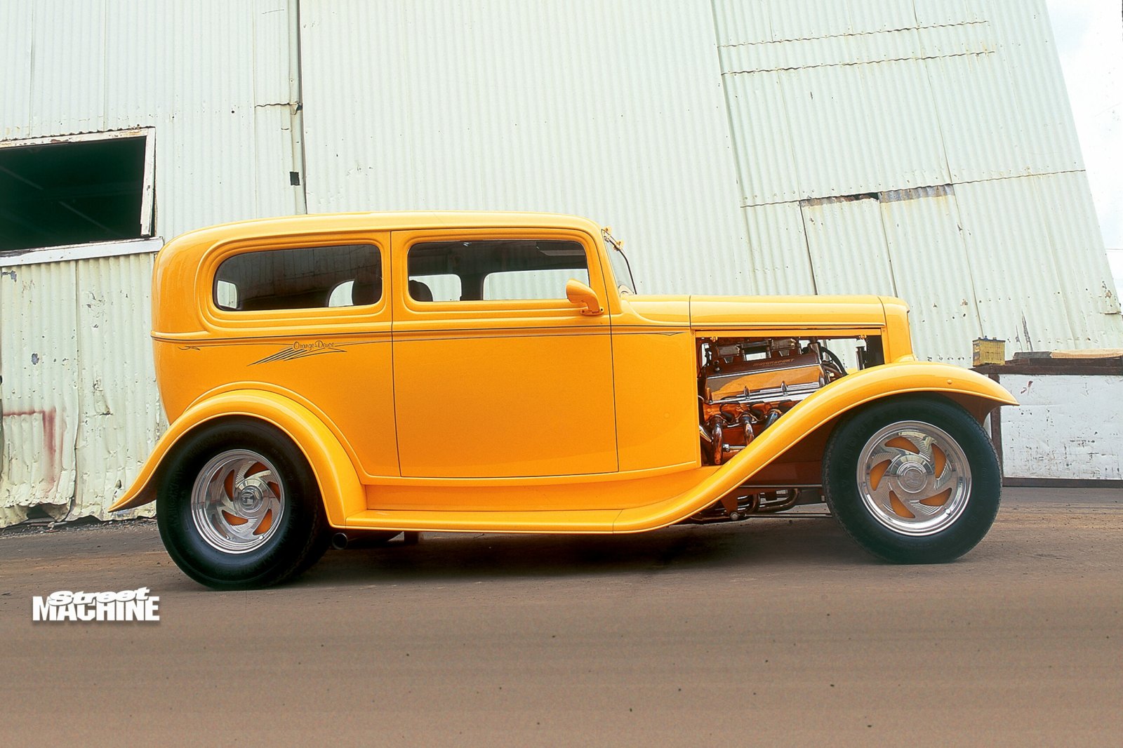 Side profile of a bright yellow classic Ford hot rod with custom wheels