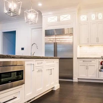 Custom white kitchen cabinetry with built-in stainless steel refrigerator