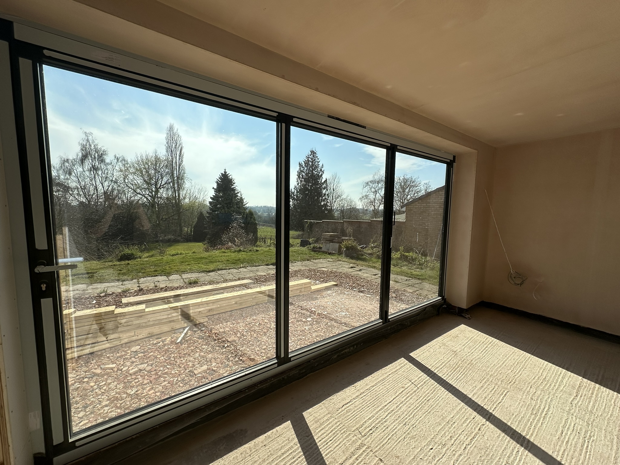 Large aluminium sliding doors installed by Milano Home Improvement in Halesowen, creating a bright open-plan living space with uninterrupted garden views.