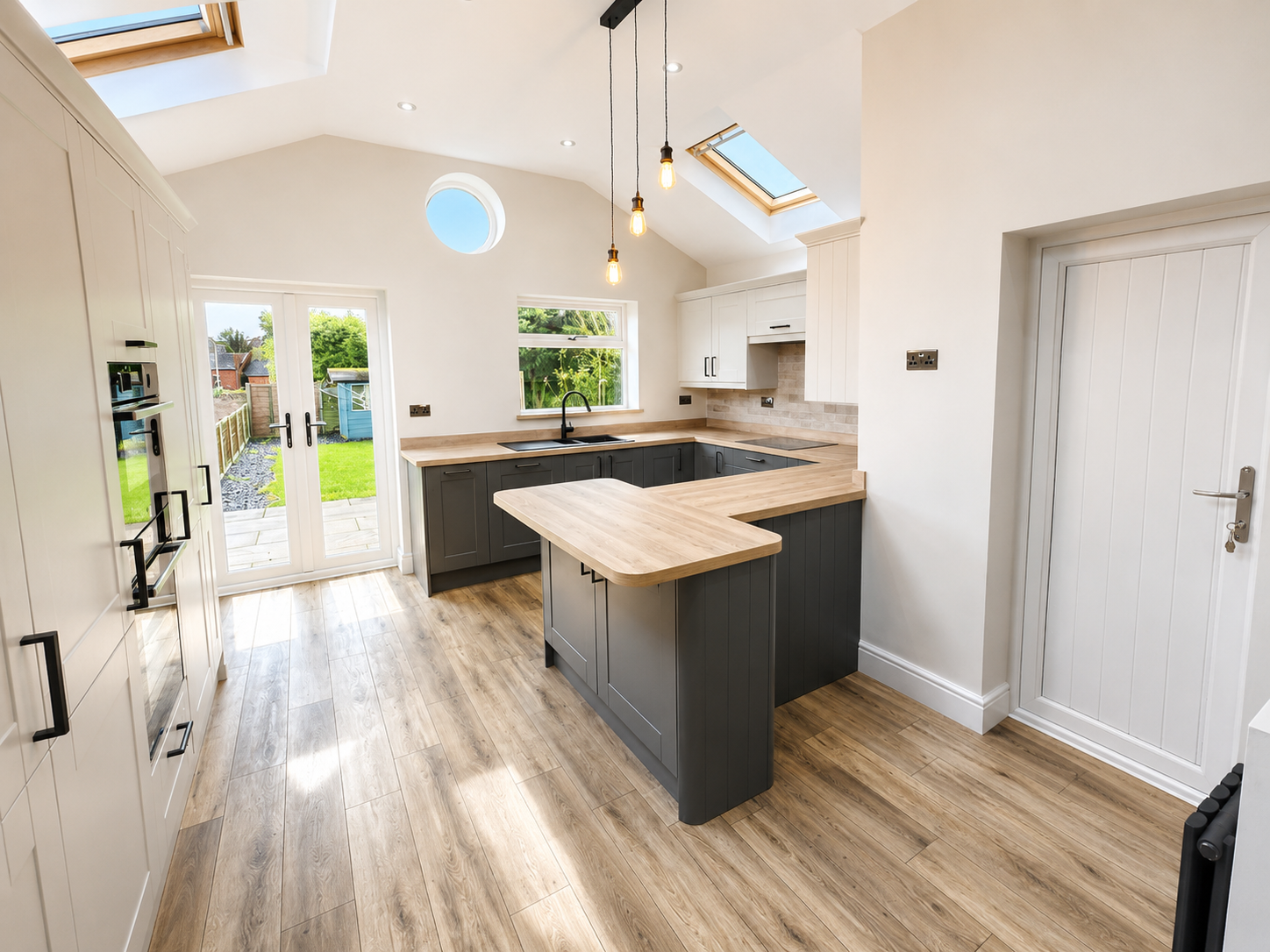 Open-plan kitchen renovation completed by Milano Home Improvement in Halesowen, featuring a modern shaker kitchen, vaulted ceiling, rooflights and French doors.