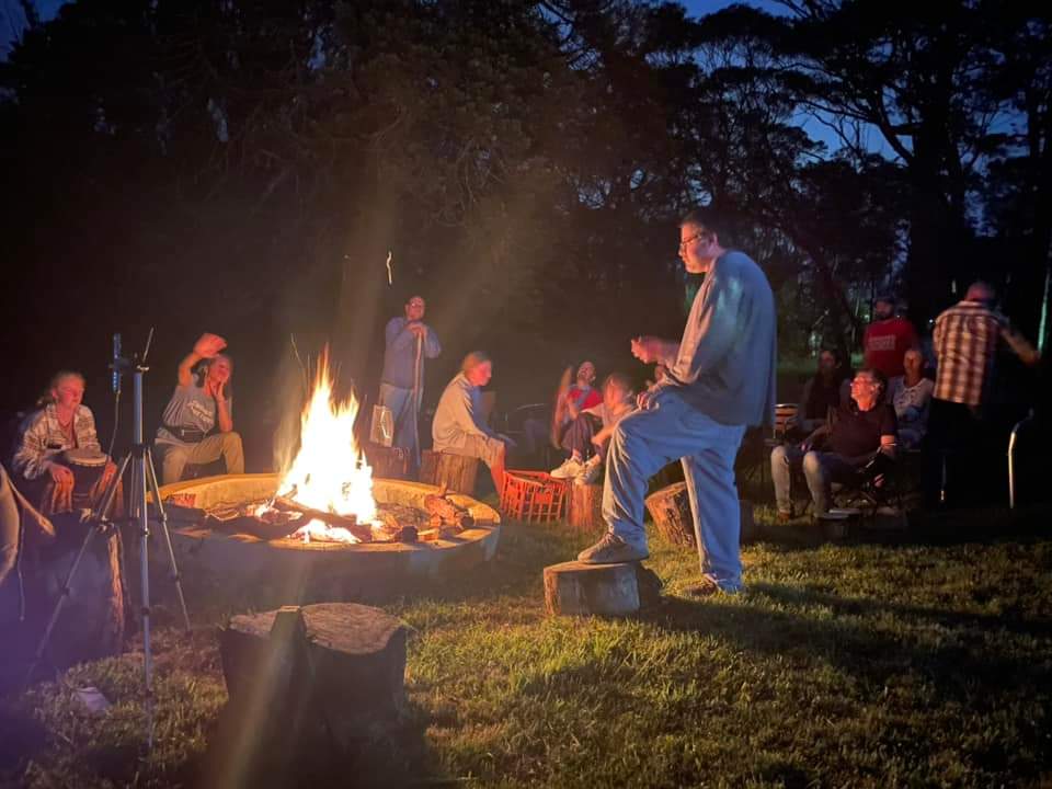 People gathered around a campfire at night, praying and worshipping