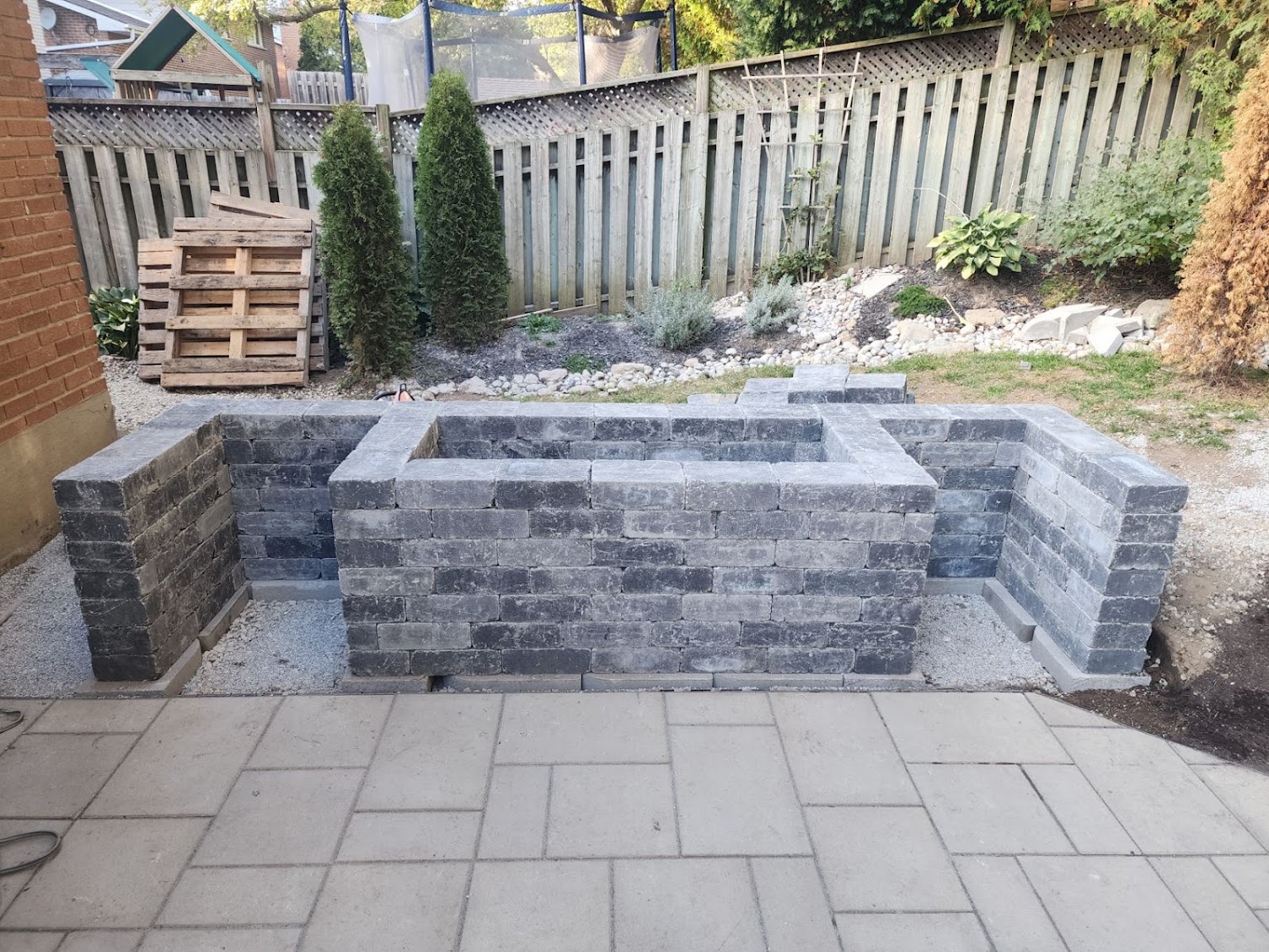 Custom stone planter box and retaining block structure under construction on patio in London, Ontario