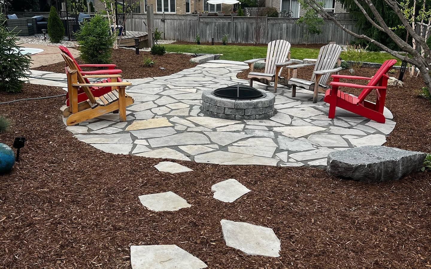 Backyard stone patio and fire pit design in London, ON