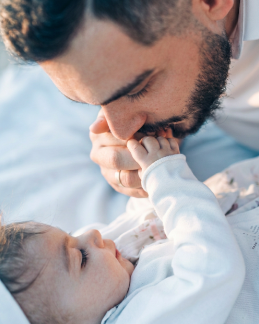 A father kissing his baby's hand, representing the deep connection and joy of building a family.