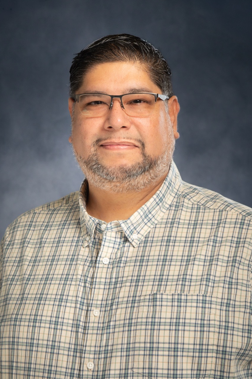 Professional studio headshot — male professional in plaid shirt