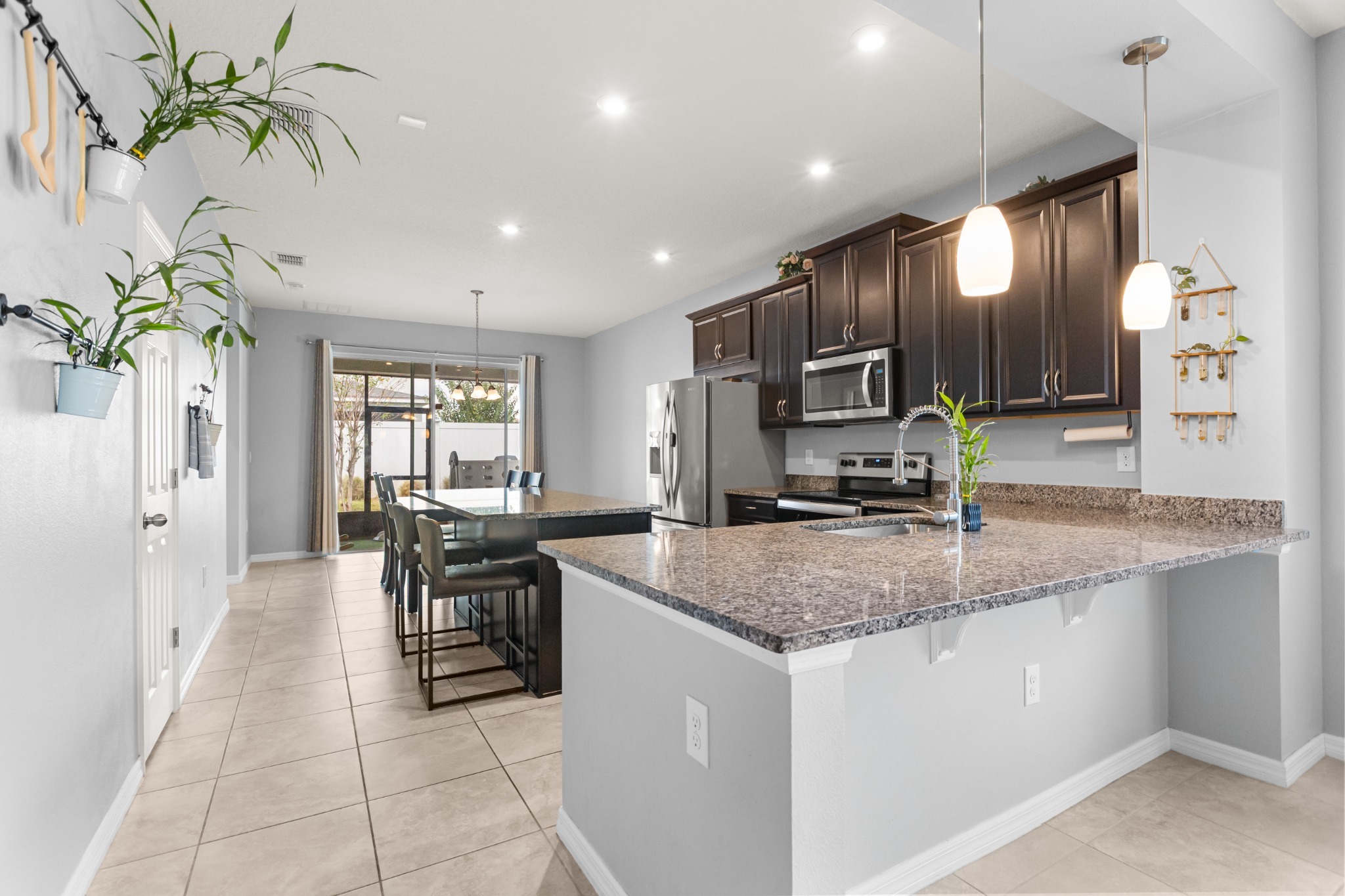 2401 Avian Loop Kissimmee FL - Kitchen perspective showing prep island with bar seating, pendant lighting, and stainless steel appliances