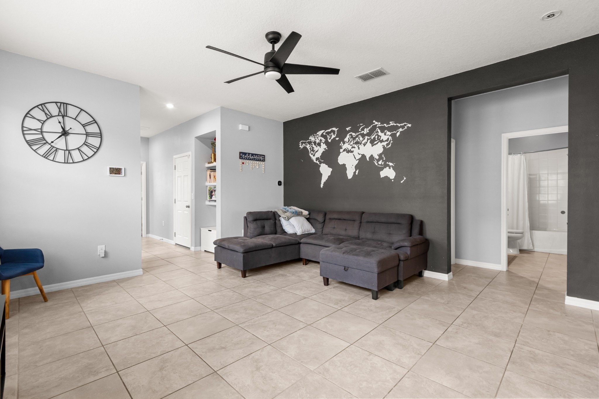 2401 Avian Loop Kissimmee FL - Living area gathering space showing ceramic tile flooring, ceiling fan, accent wall, and hallway access