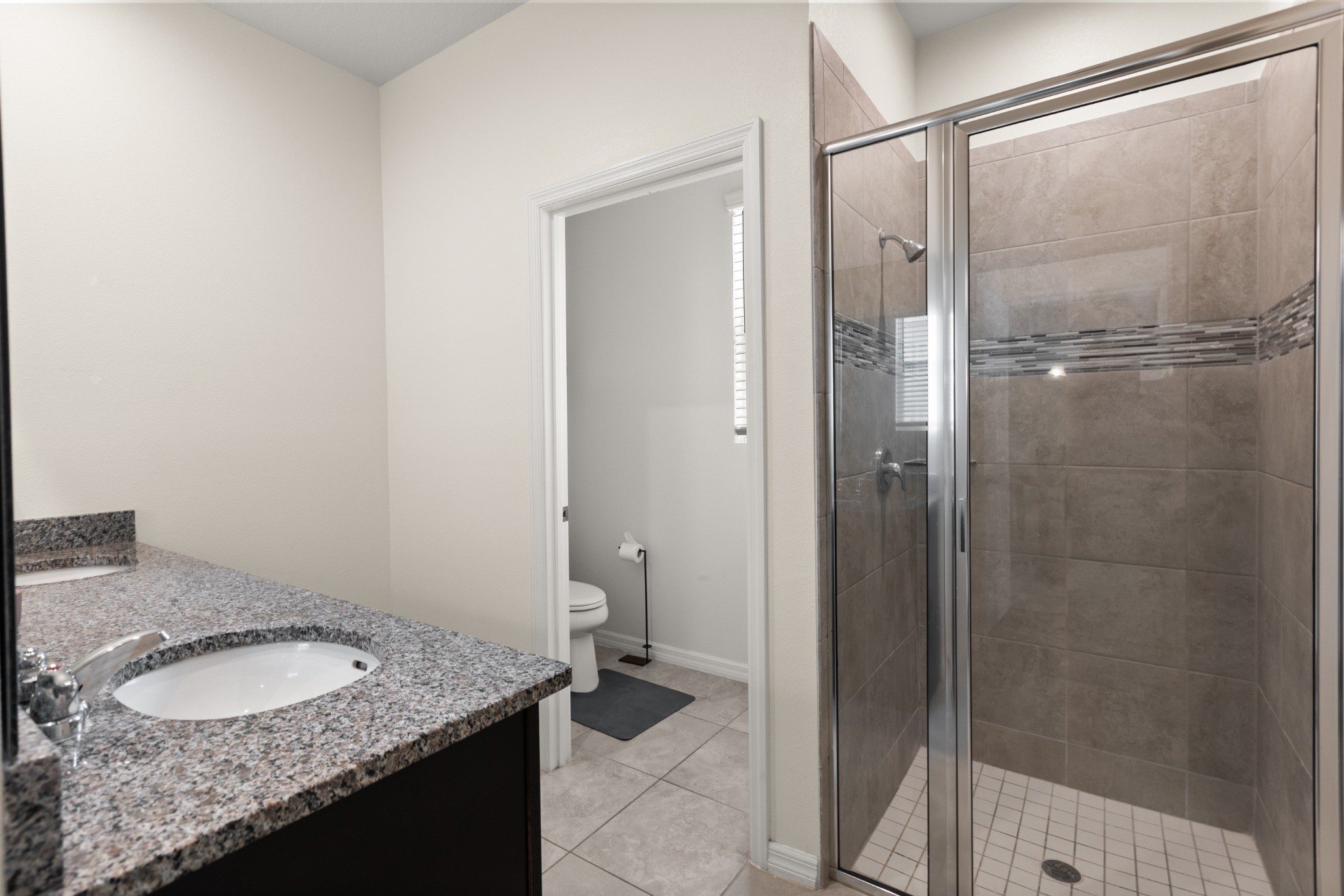 2401 Avian Loop Kissimmee FL - Primary bathroom with granite vanity, walk-in tiled shower, and separate toilet area